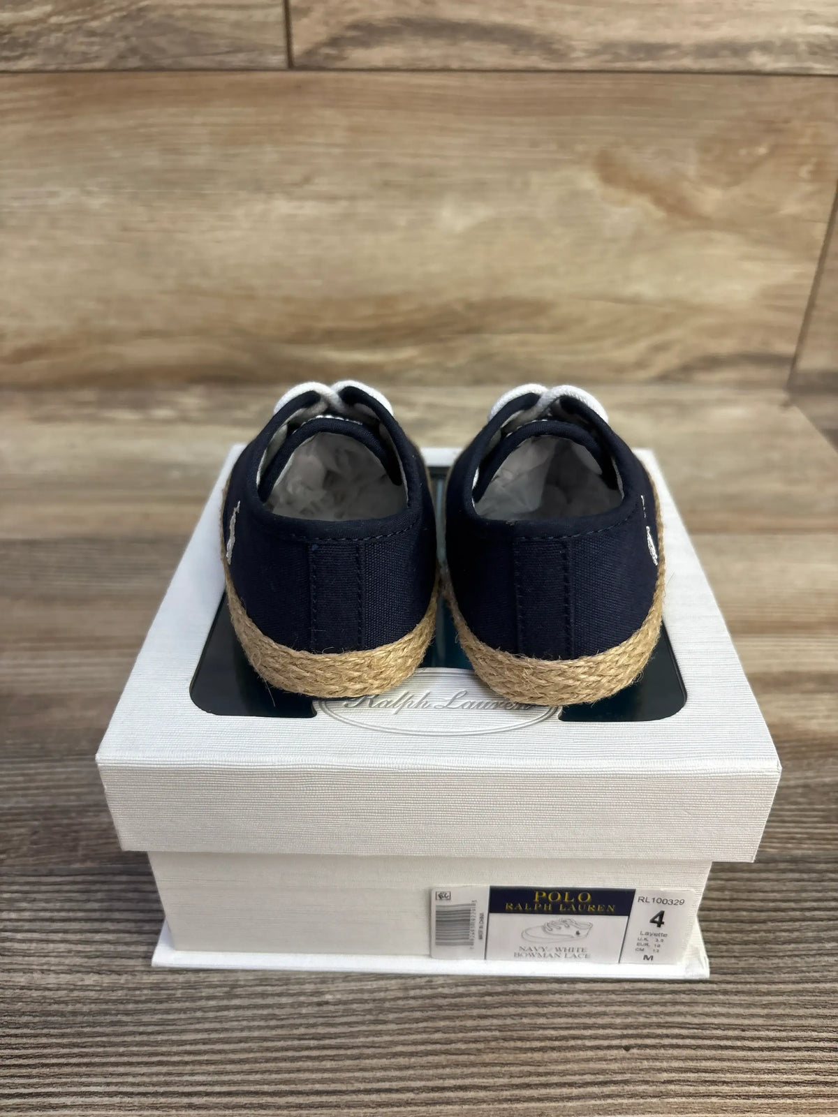 Rear view of Ralph Lauren Bowman navy lace crib shoes showcasing rope-textured soles on a branded box