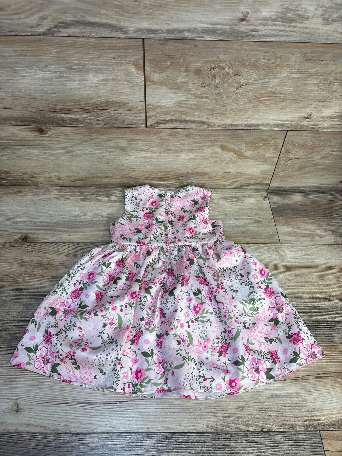 Pink floral sleeveless toddler dress with gathered waist, displayed on wood floor