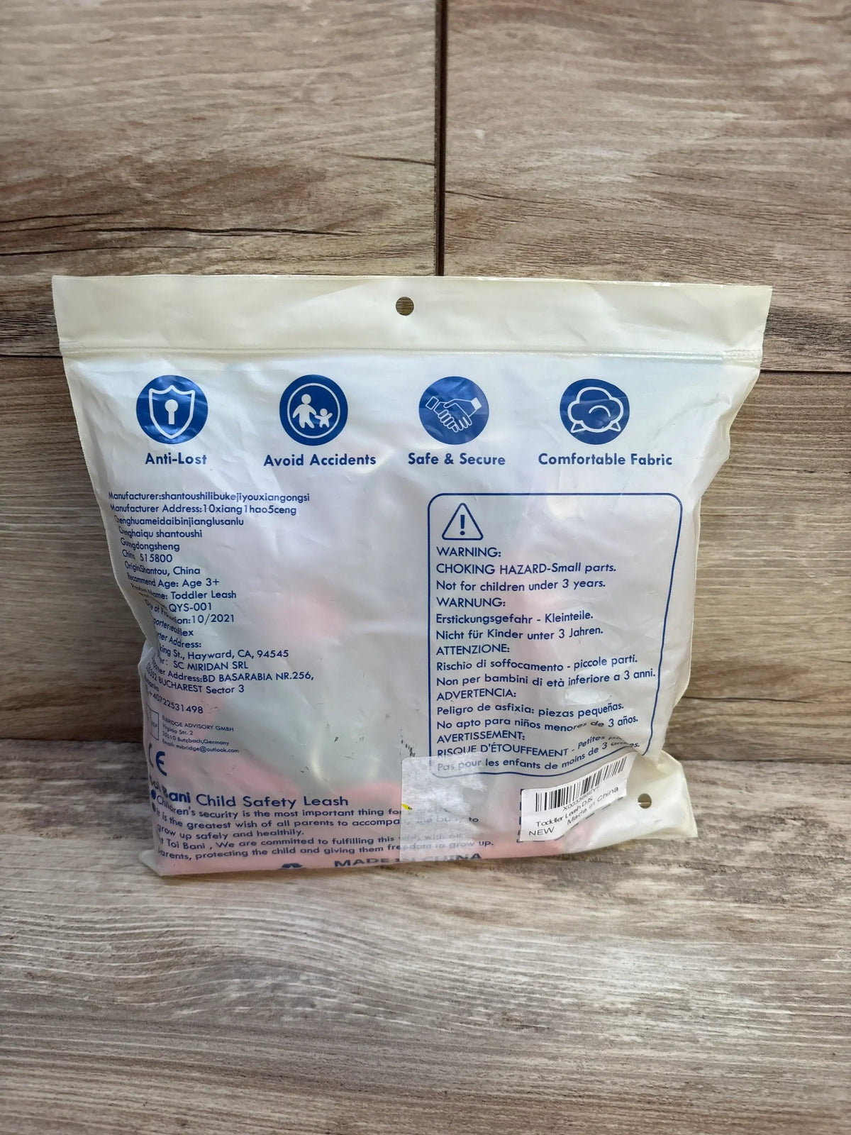 Back of NEW Toi Bani 4-in-1 toddler safety harness leash packaging showing safety icons and warning label on a wood floor