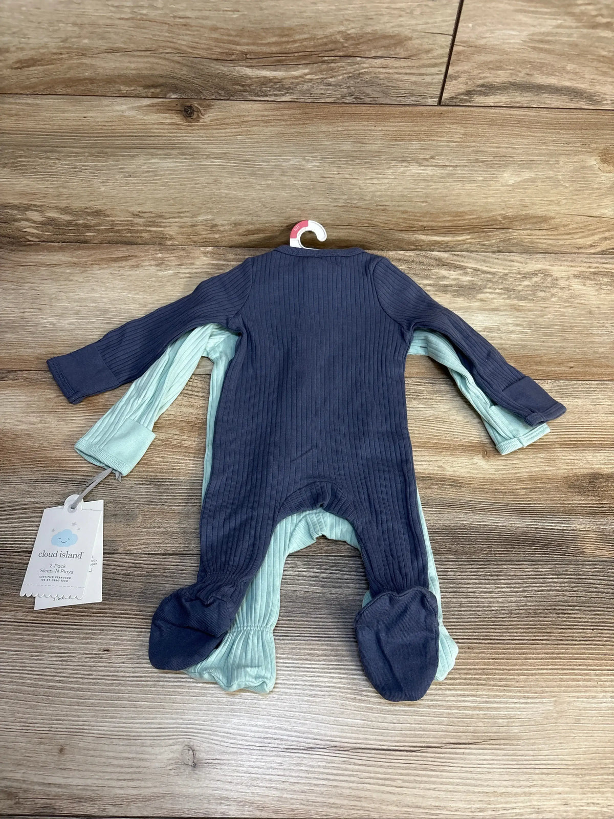 Top-down view of two Cloud Island ribbed footed sleepers (2-pack) in navy and turquoise with ribbed texture on wood background