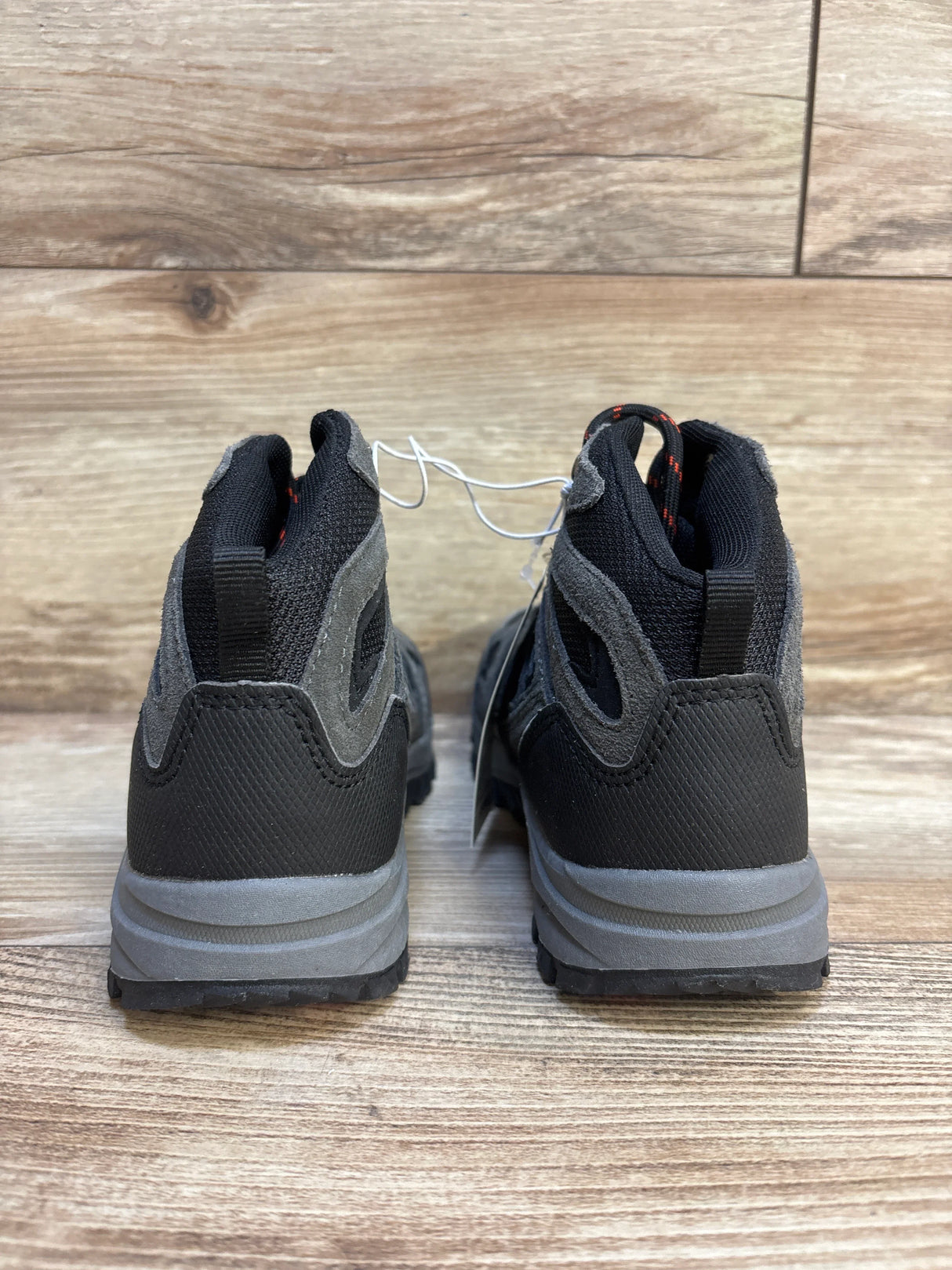 Pair of black and gray kids' athletic sneakers on wooden floor, rear view