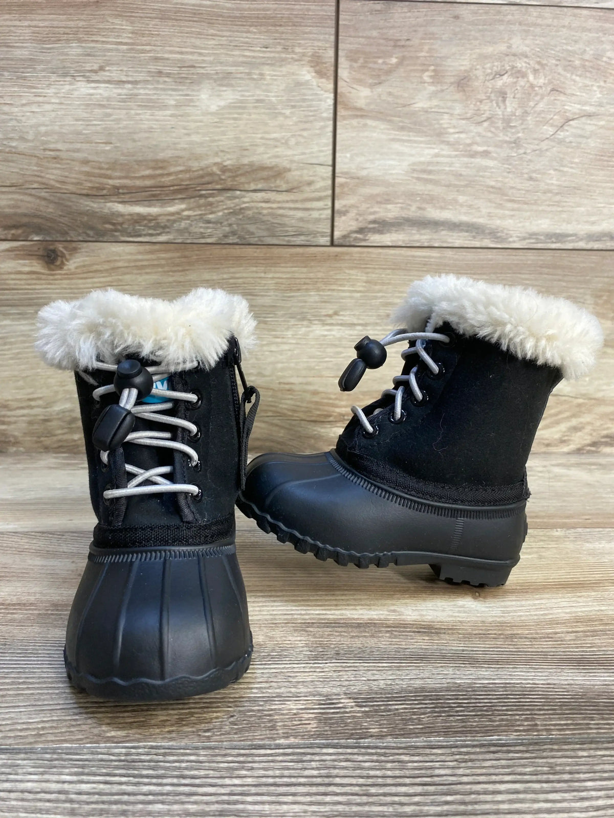 Black toddler winter boots with faux fur lining and rubber soles on wood floor