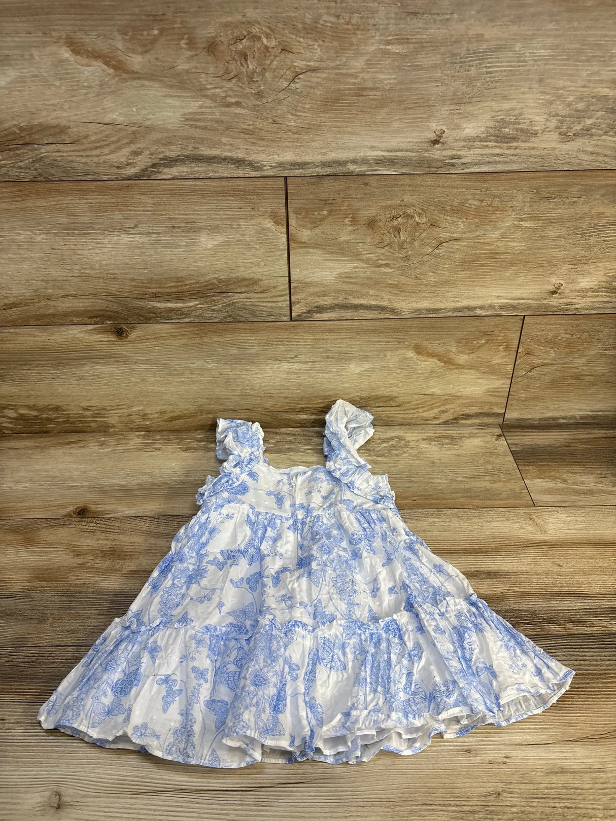Girls ruffle sleeve dress with blue floral print, gently used kids clothing on wood floor