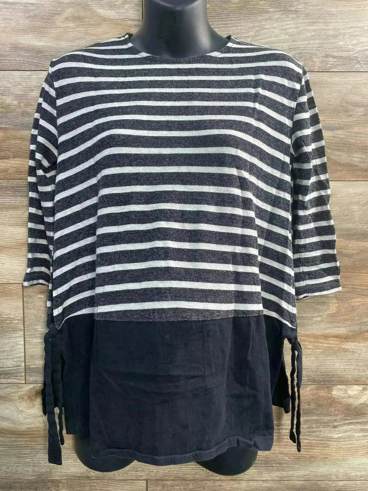 Front view of ASOS maternity striped top with black lower panel and side ties on a mannequin against wood background