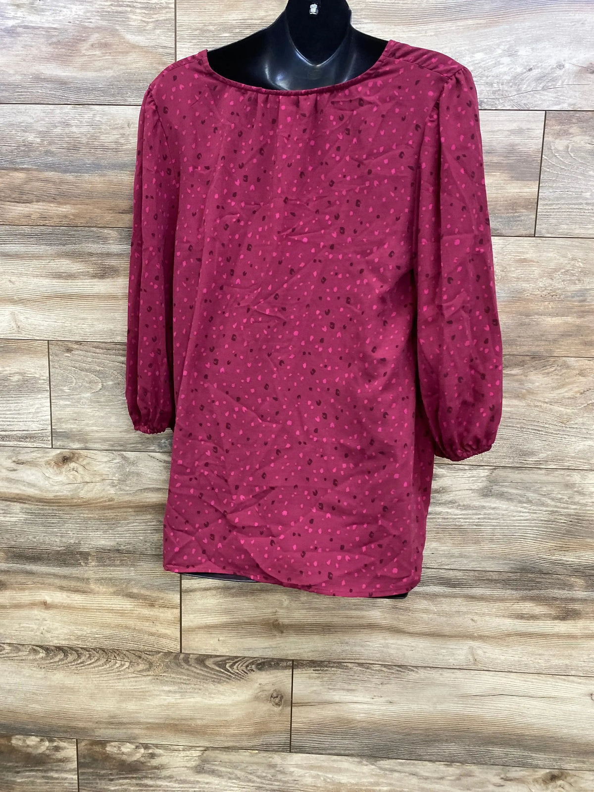Front view of Isabel maternity ruffle-waist top in berry showing 3/4 elastic sleeves and small dot print on wood background