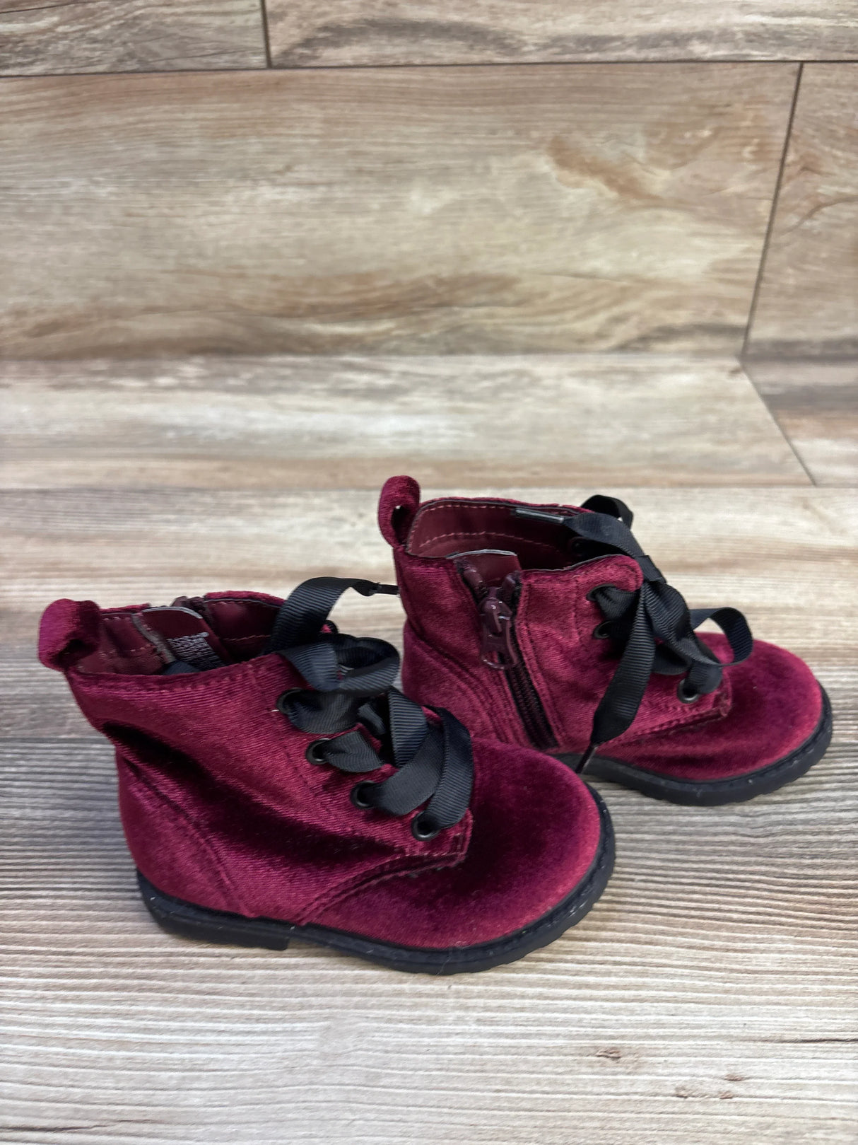 Front three-quarter view of Cat & Jack velvet toddler boots in burgundy showing black ribbon laces and side zipper on wood floor