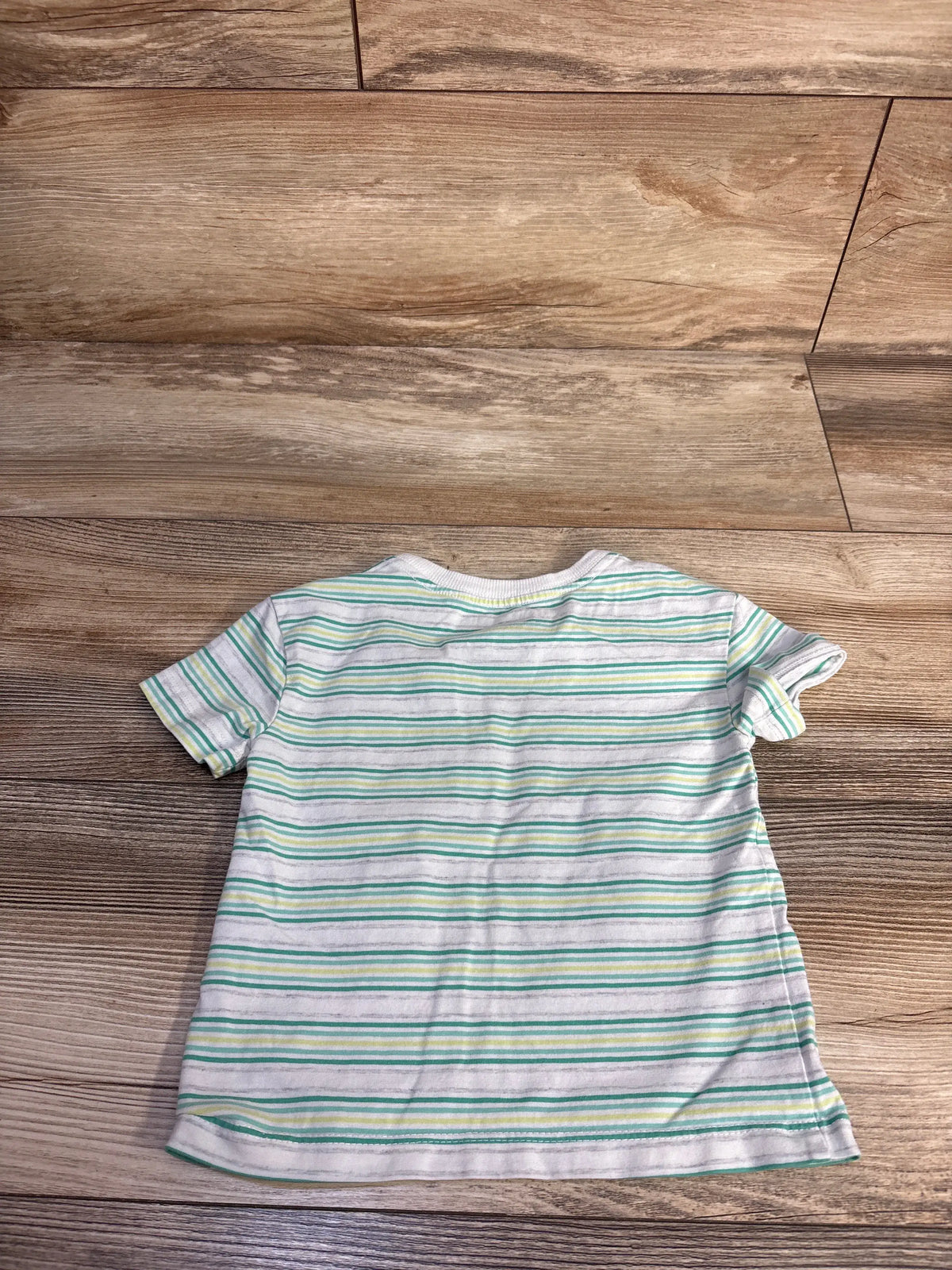 Back view of Flapdoodles striped shirt in white, size 12 months, with green, gray, and yellow stripes on a wood floor
