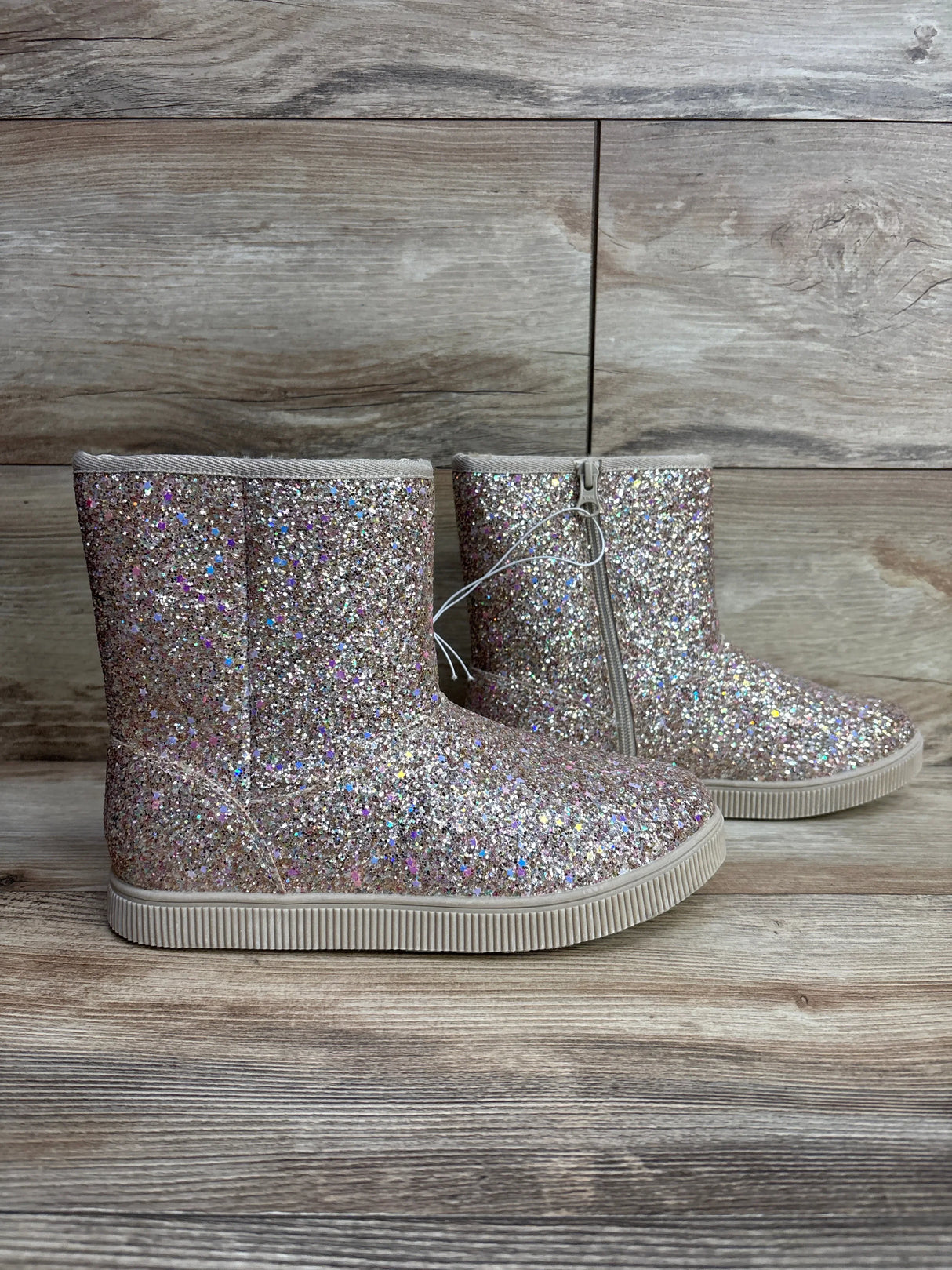 Sparkly glitter kids boots with side zipper on wood background, children's footwear