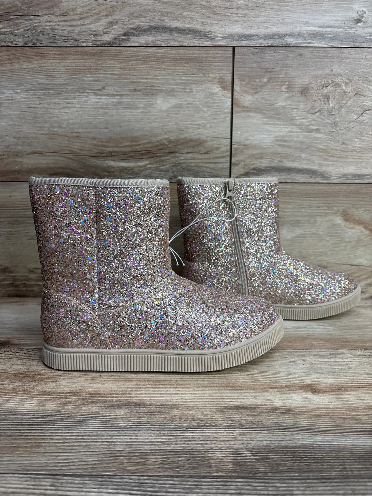 Side view of Cat & Jack Holland shearling-style glittery gold kids boots showing side zipper on wooden background