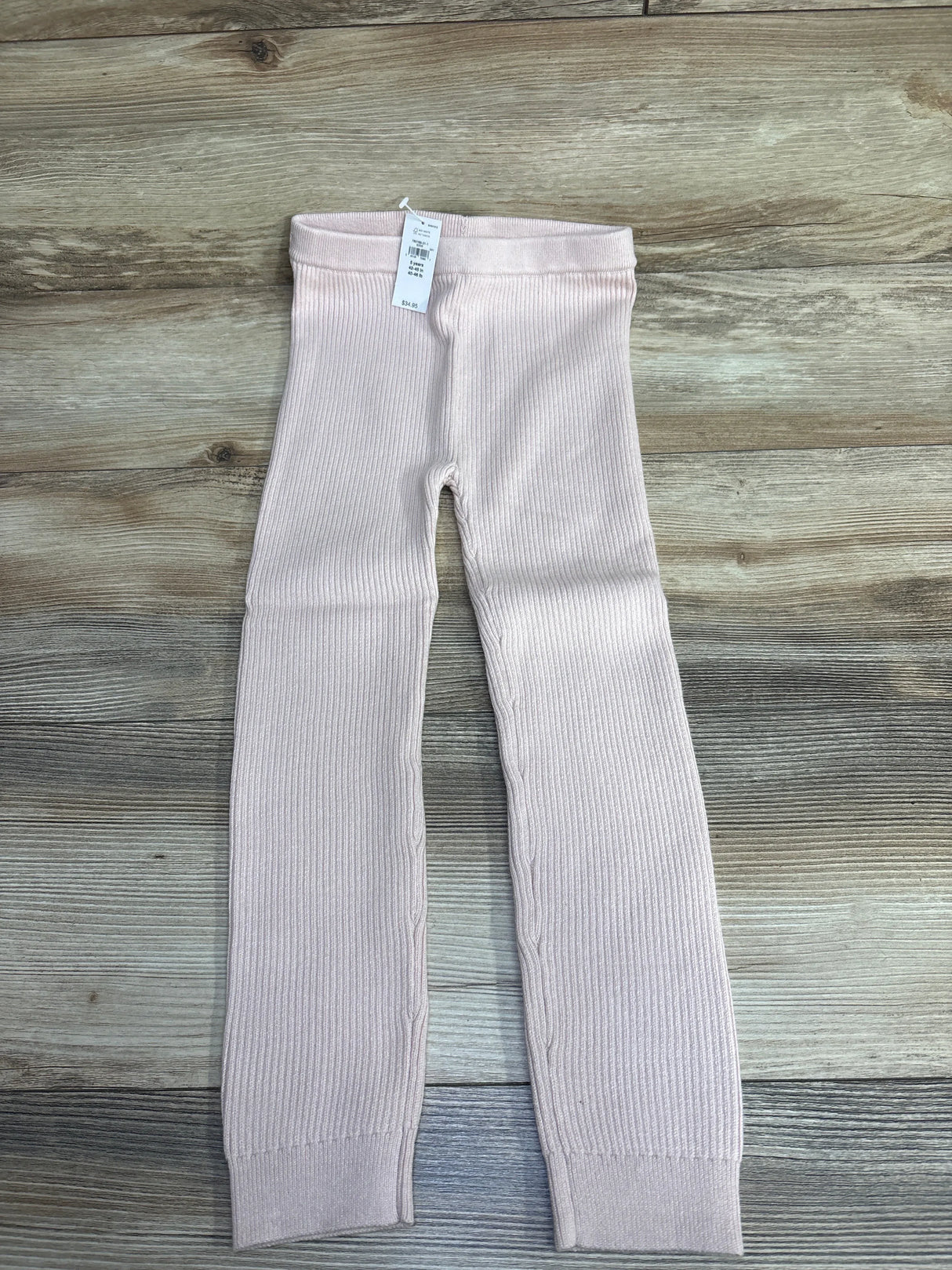Light pink ribbed toddler leggings with elastic waistband on wood background