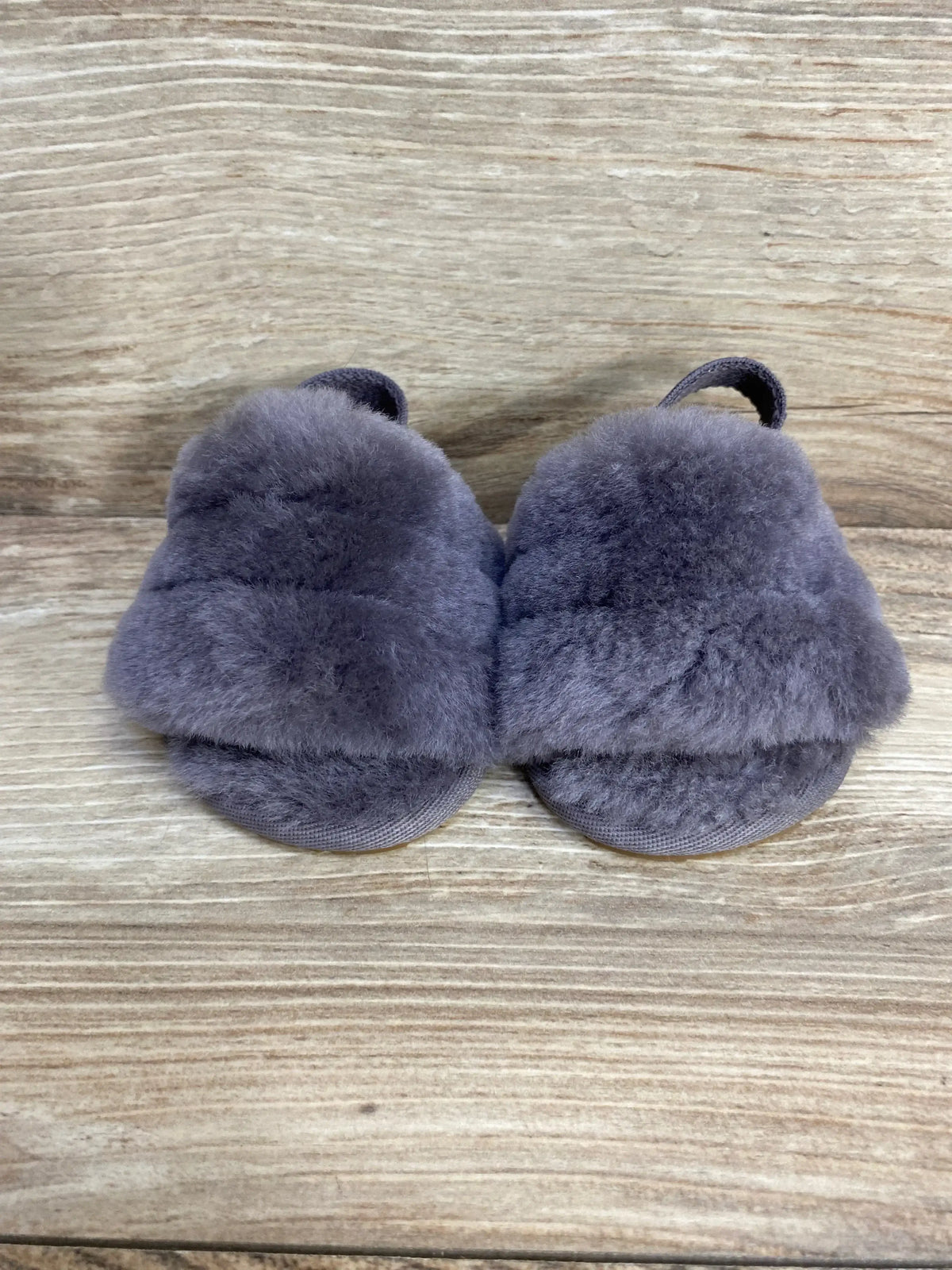 Front view of UGG Fluff Yeah toddler slides in grey showing plush shearling upper and elastic heel strap on wood background