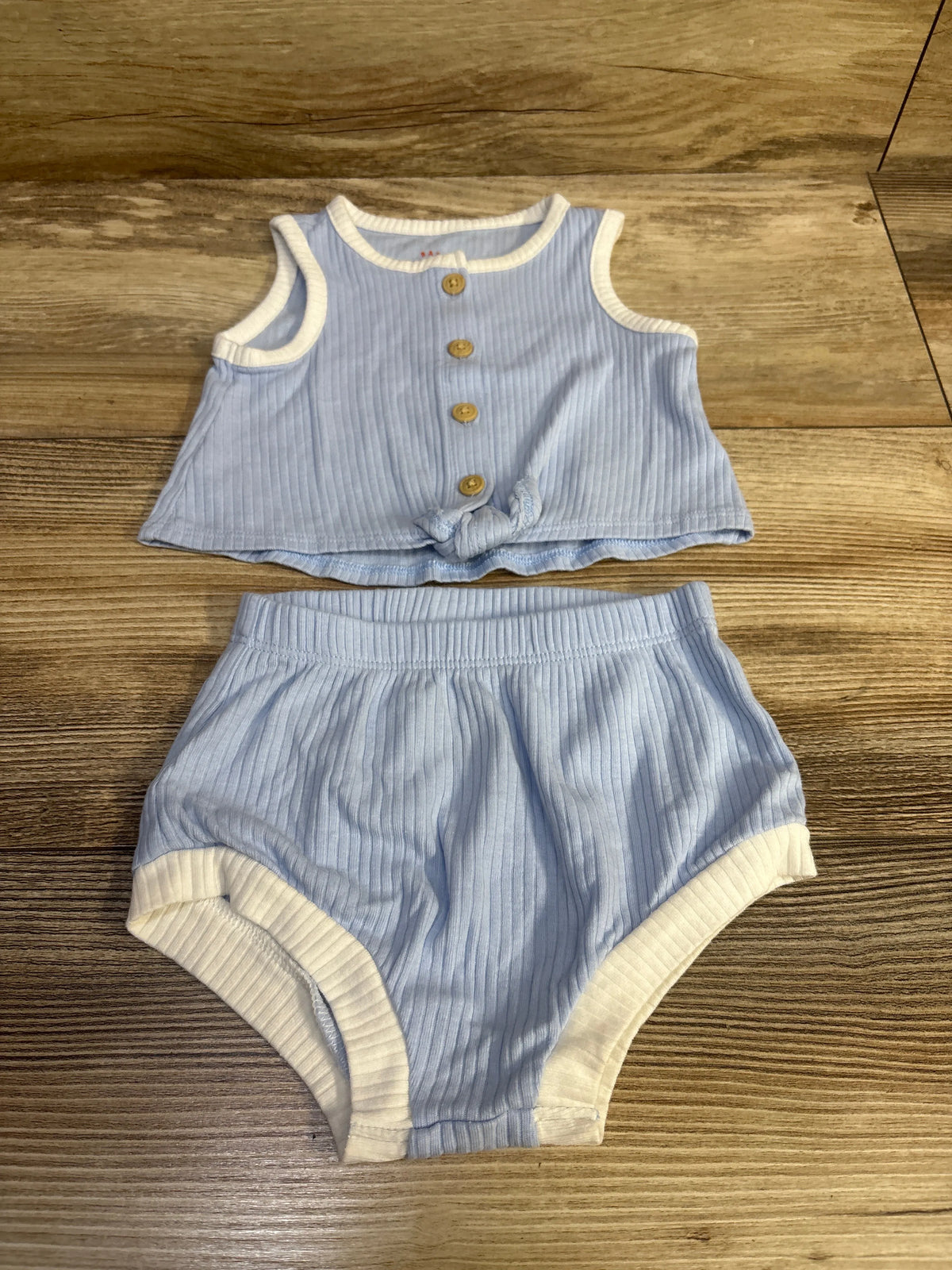 Flat lay of ribbed tank top and matching bloomers with wood buttons, knotted hem, white trim and elastic waist on wood