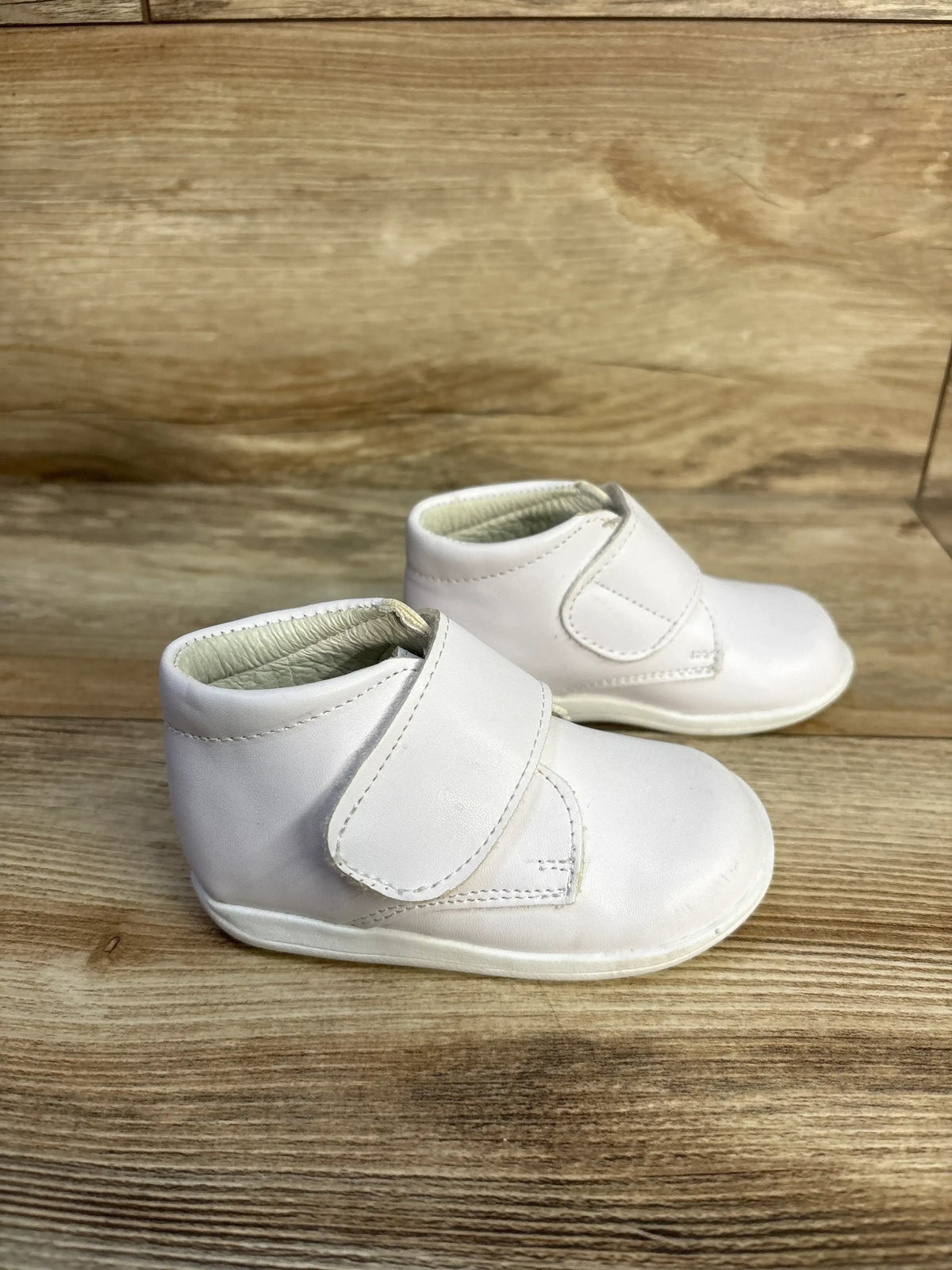 Pair of Alegria Kids patent leather white first walker shoes with hook-and-loop straps.