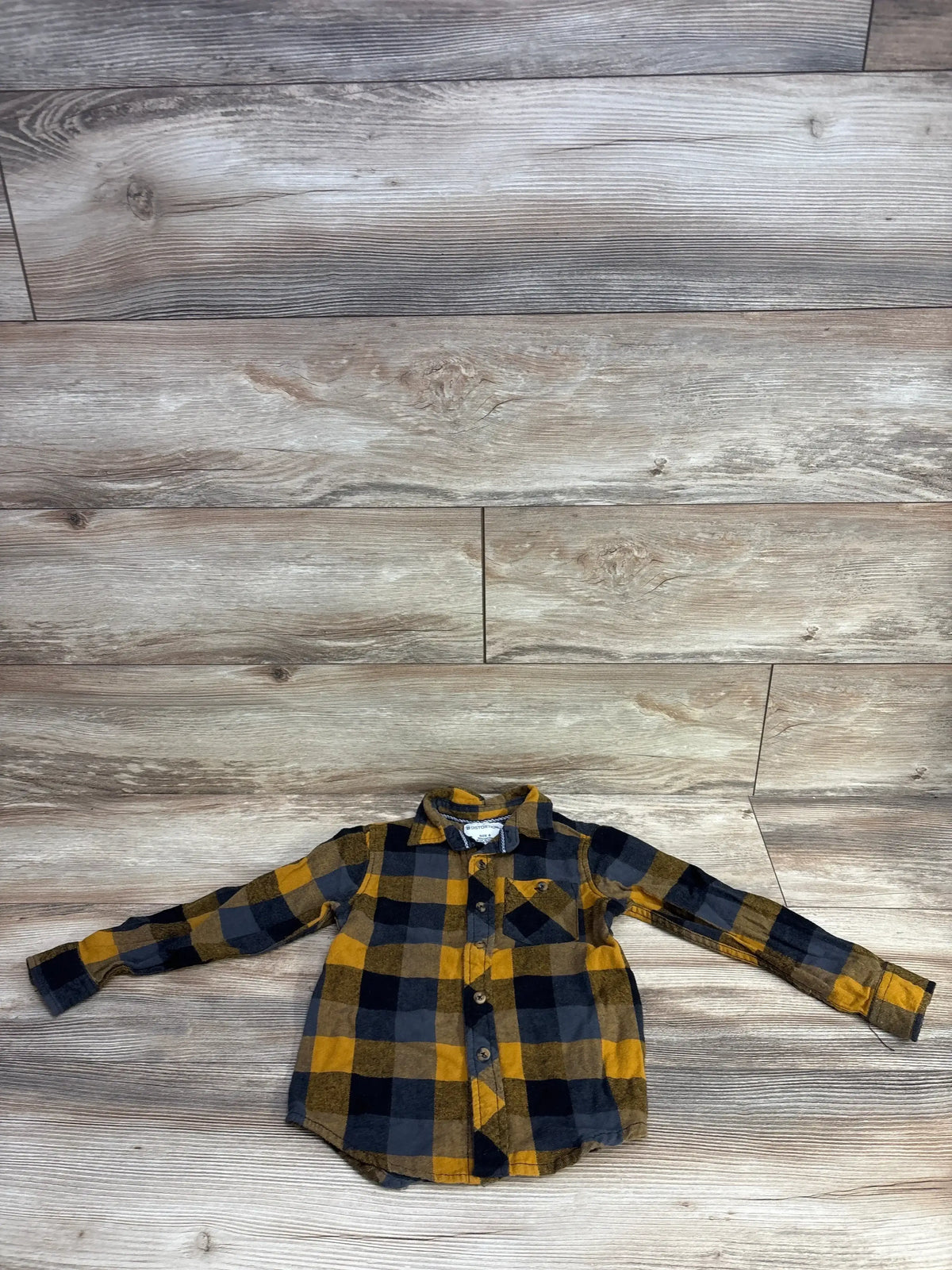 Children's long-sleeve flannel shirt in yellow, black, and gray plaid on wood floor