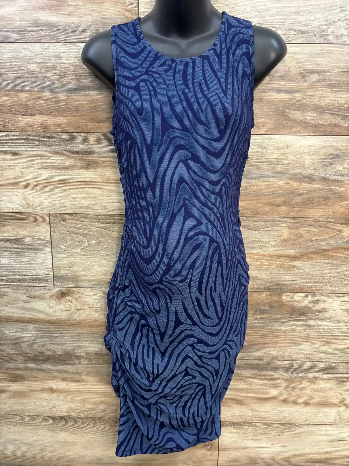 Front view of blue textured maternity bodycon dress with zebra-like pattern and side ruching on wooden background