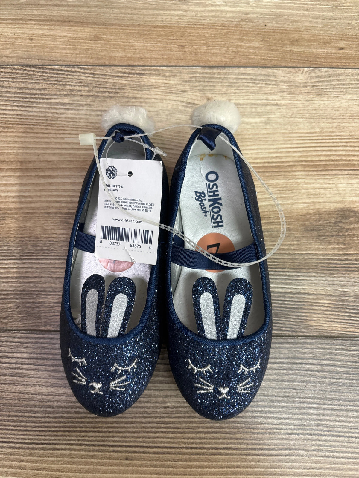 Pair of navy glittery Oshkosh baby flats featuring bunny faces and white pom-poms.