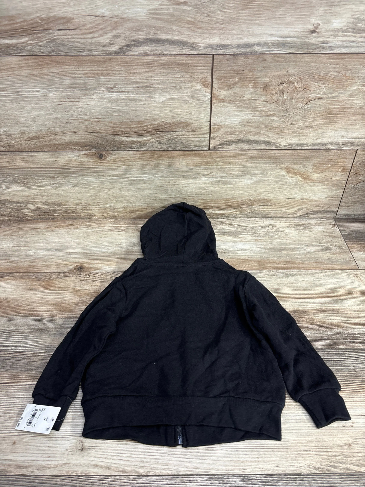Back view of NEW Marvel Black Panther full zip hoodie in black with hood up and white retail hangtag on sleeve over wood plank floor
