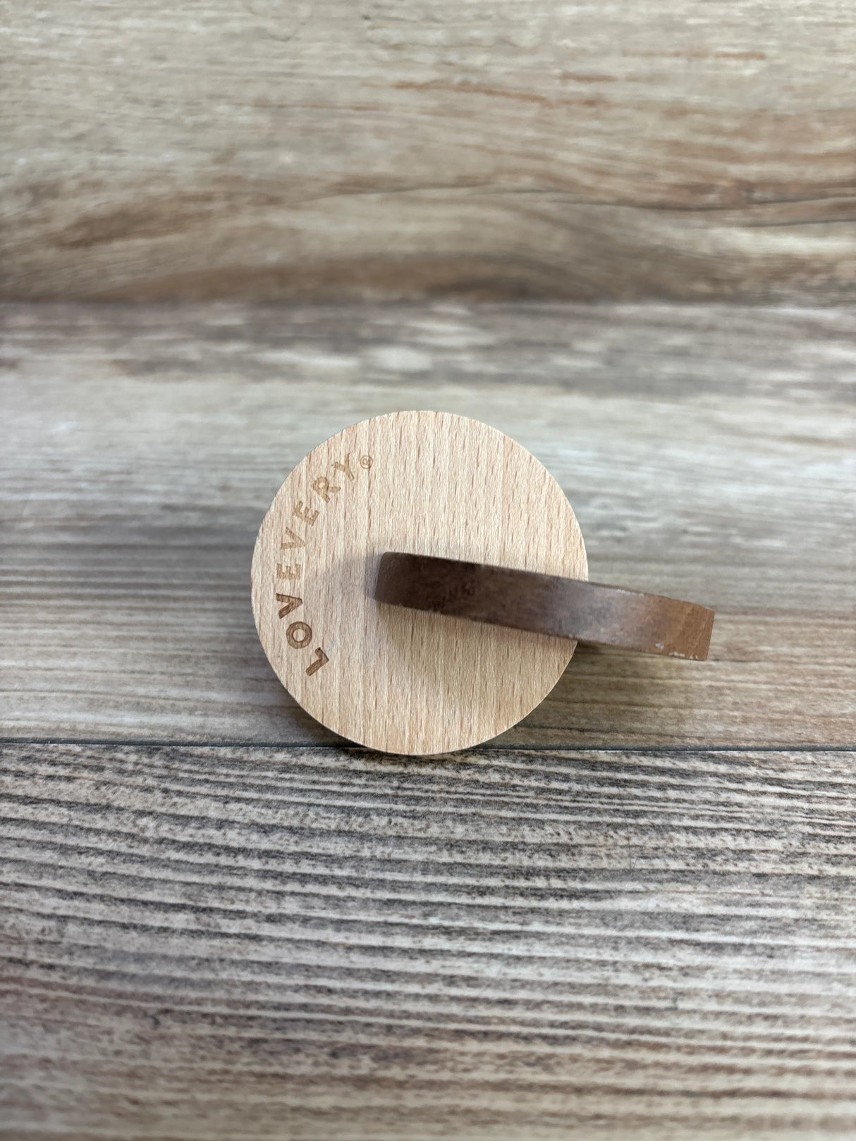 Round wooden toy with engraved text on rustic wooden surface