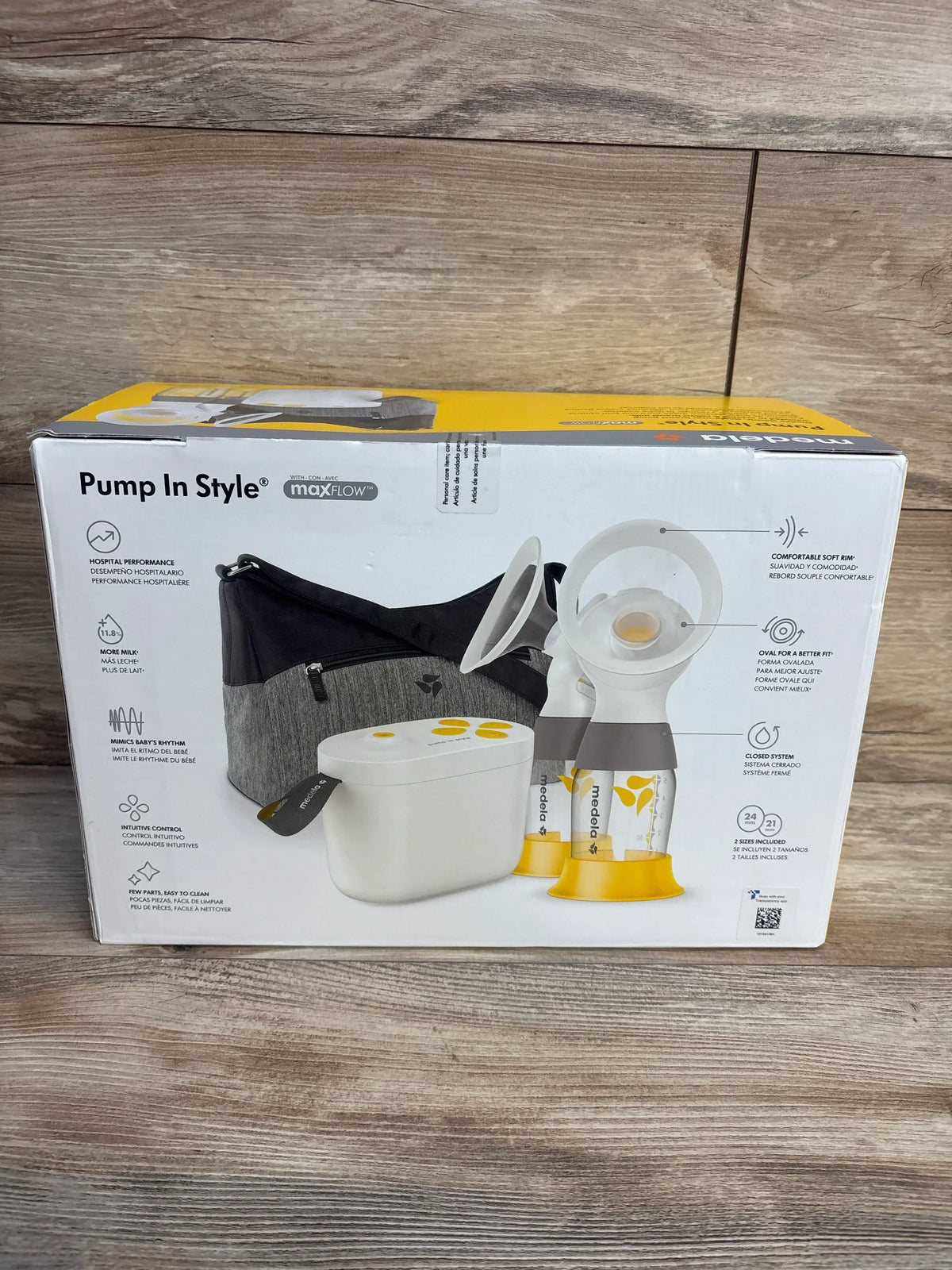 Front of boxed Medela Pump In Style with MaxFlow double electric pump showing pump unit, two yellow bottles and gray bag