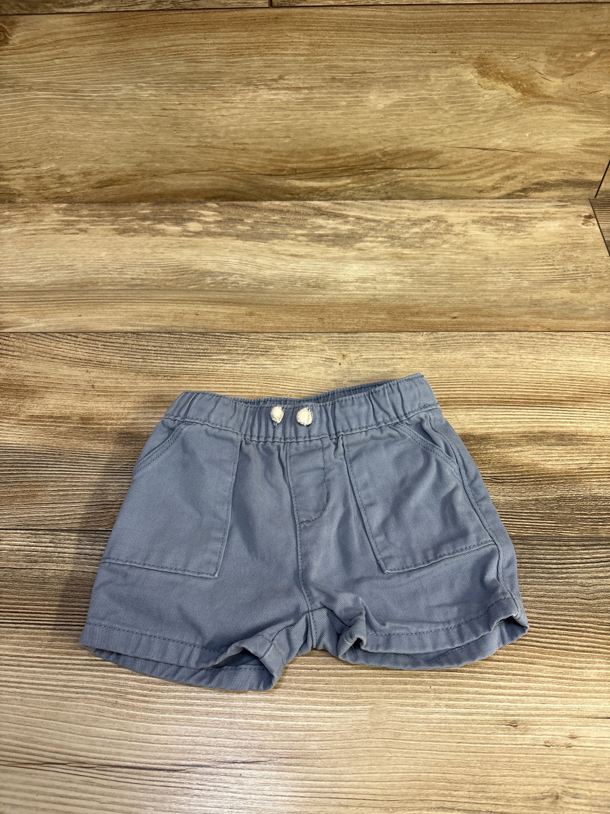 Flat lay of Old Navy baby drawstring shorts showcasing elastic drawstring waistband and front patch pockets on wood background