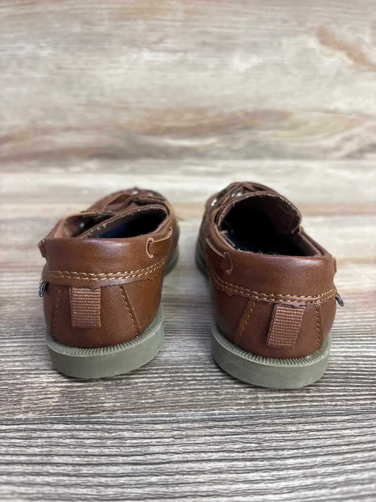 Pair of brown children's leather boat shoes with gray soles on wooden floor