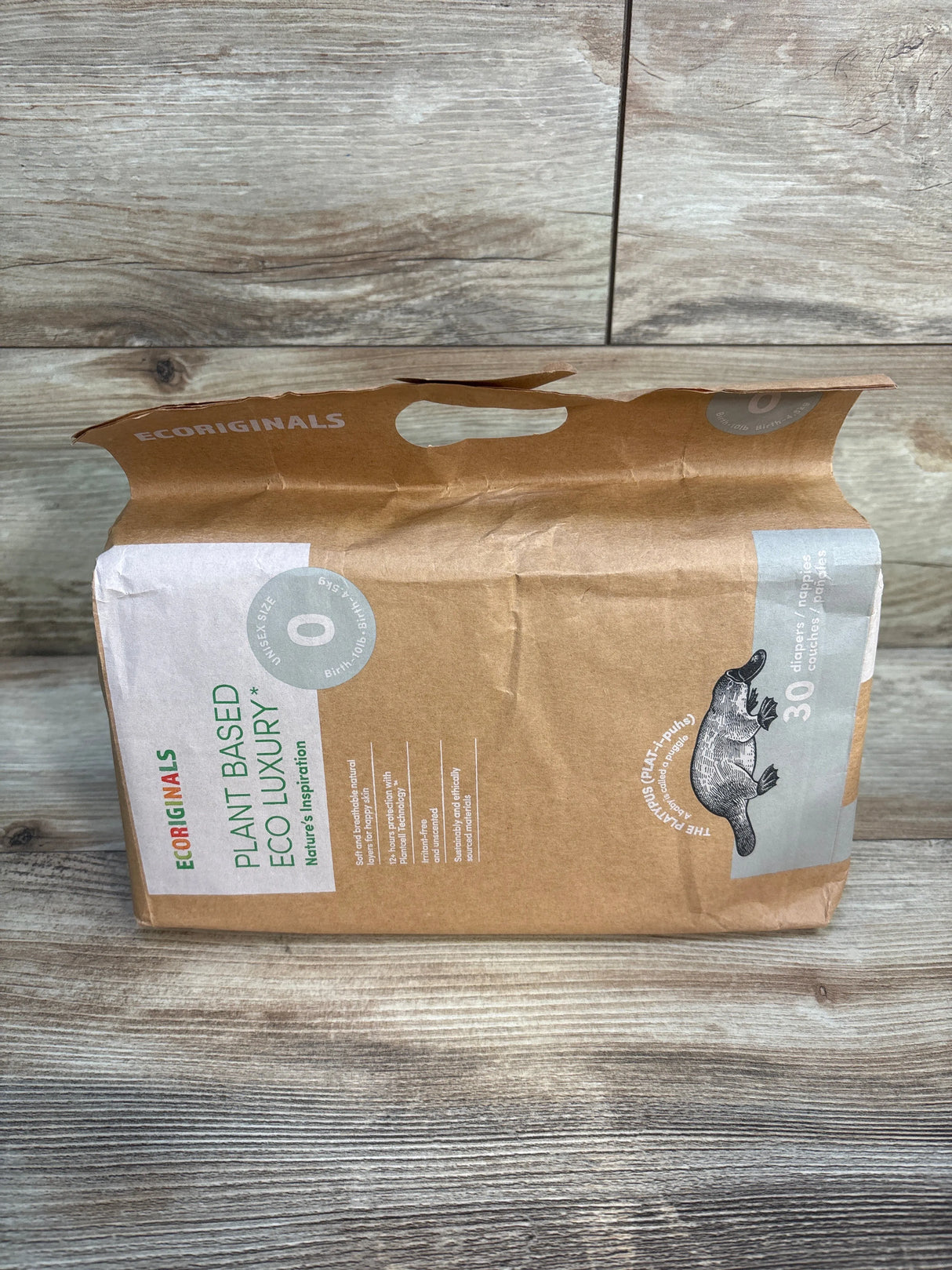Eco-friendly Ecoriginals plant based diapers pack with platypus logo on wood floor