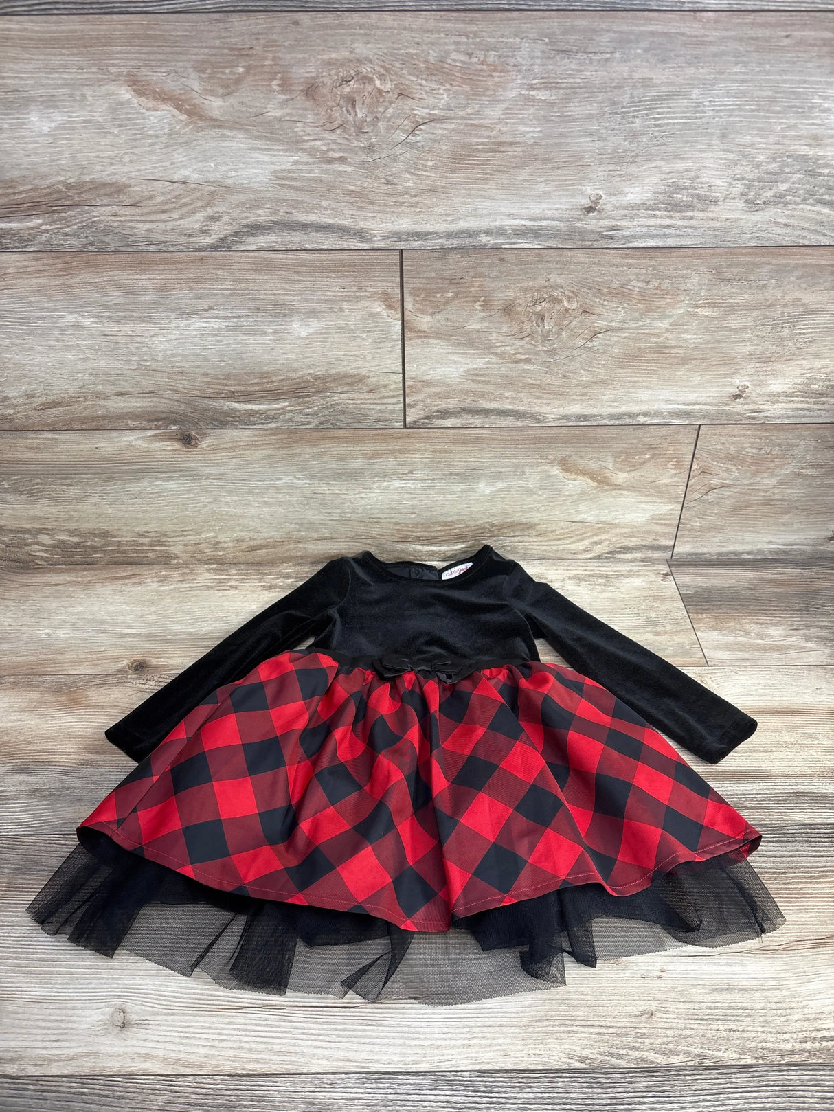 Girls' long sleeve black velvet dress with red and black plaid tulle skirt on wood floor