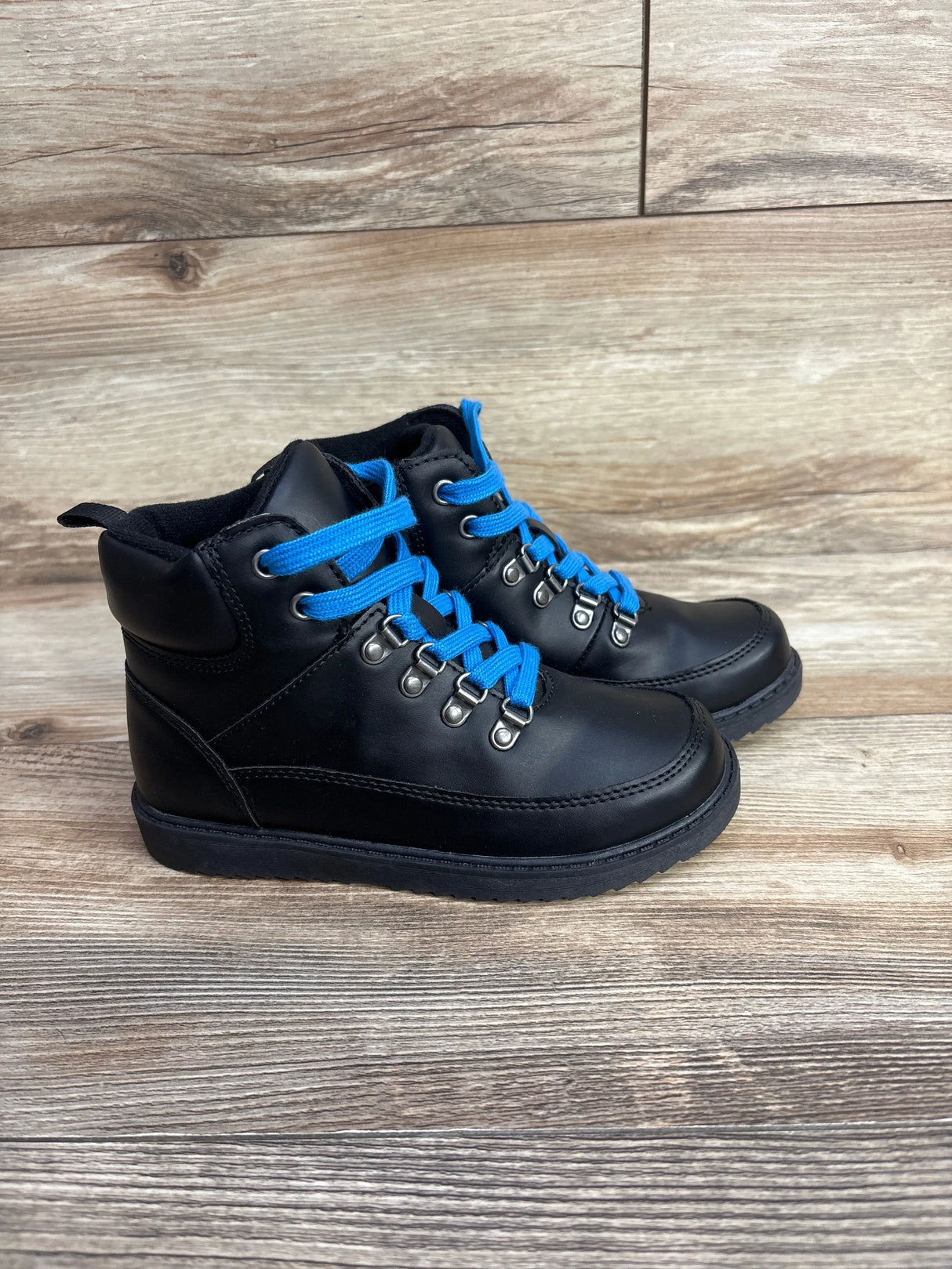 Side view of Baby Gap black toddler lace-up boots size 12C showcasing bright blue laces and metal hook eyelets on wooden floor
