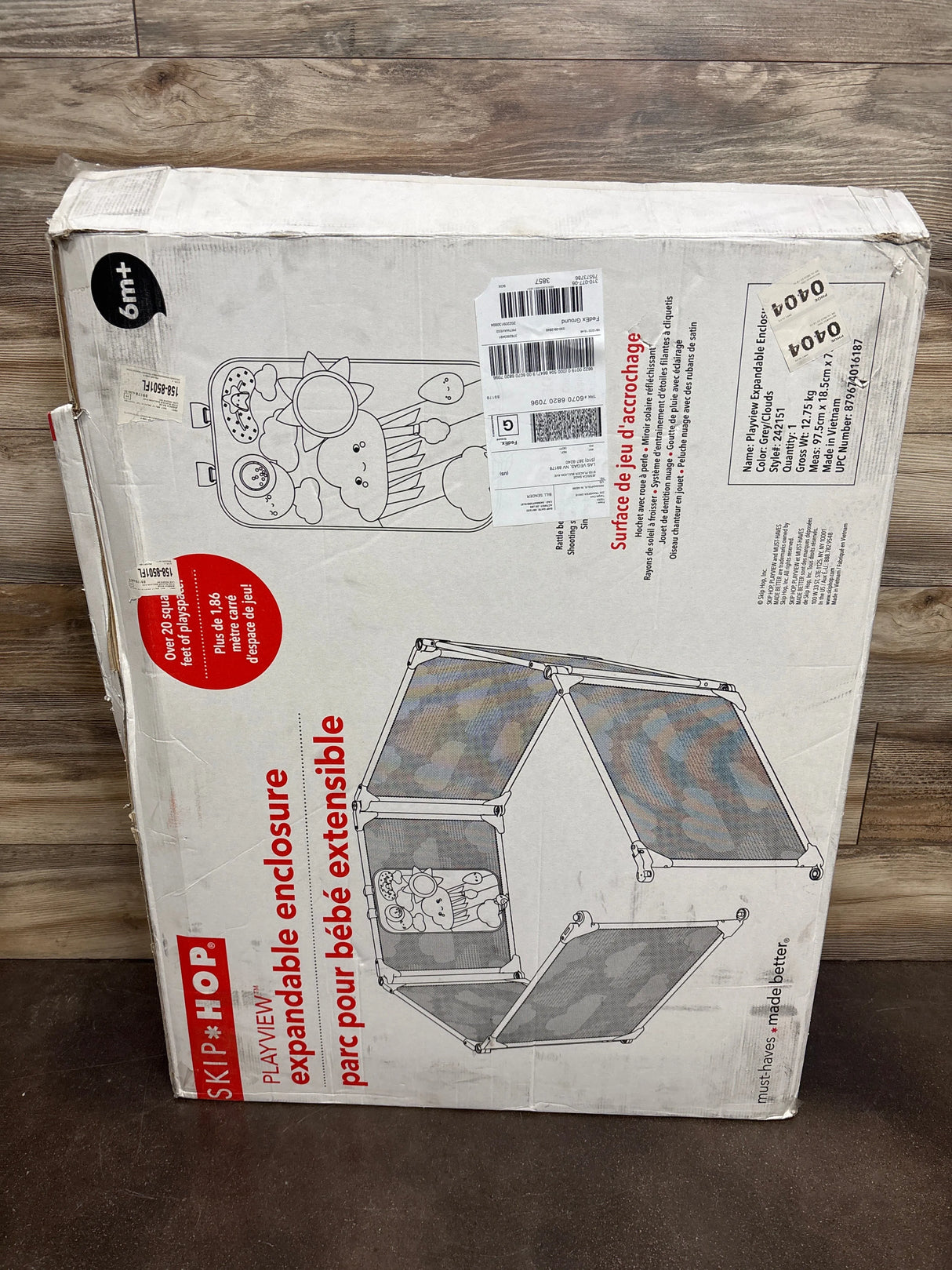 Skip Hop Playview expandable playard enclosure box on wood floor, baby gear packaging