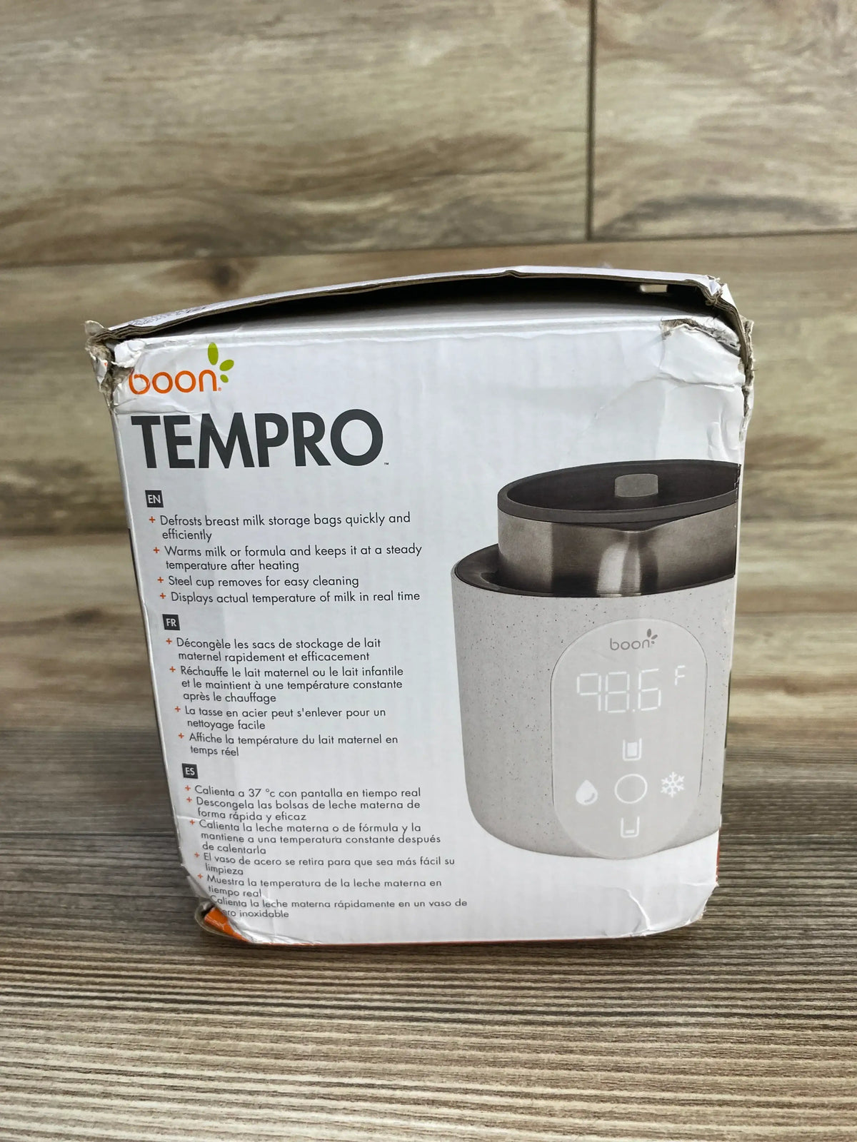 Front view of Boon Tempro Direct Heat breastmilk warmer box showing TEMPRO headline, product photo with digital temperature display and multilingual feature list on a wooden surface
