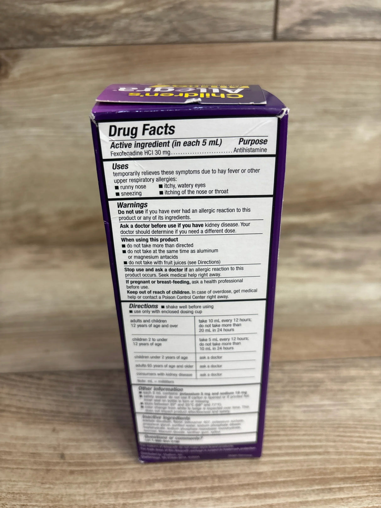 Close-up of drug facts label on purple children's allergy medicine box showing active ingredient and usage instructions