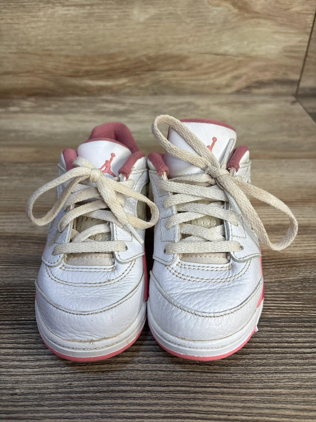 Front view of Air Jordan 5 Retro Low TD sneakers size 9C showing white leather with pink accents and tied laces on wood floor