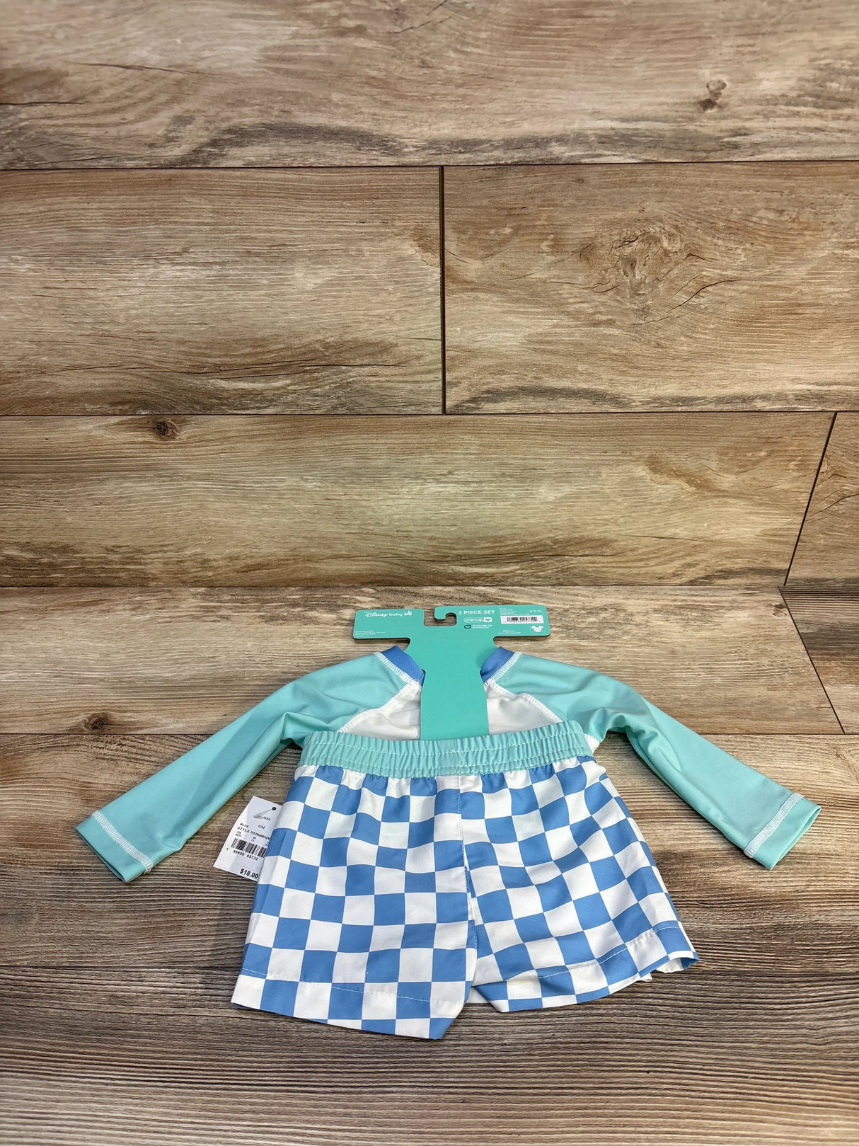 Toddler swim set with aqua long sleeve rash guard and blue checkered swim shorts on wood floor