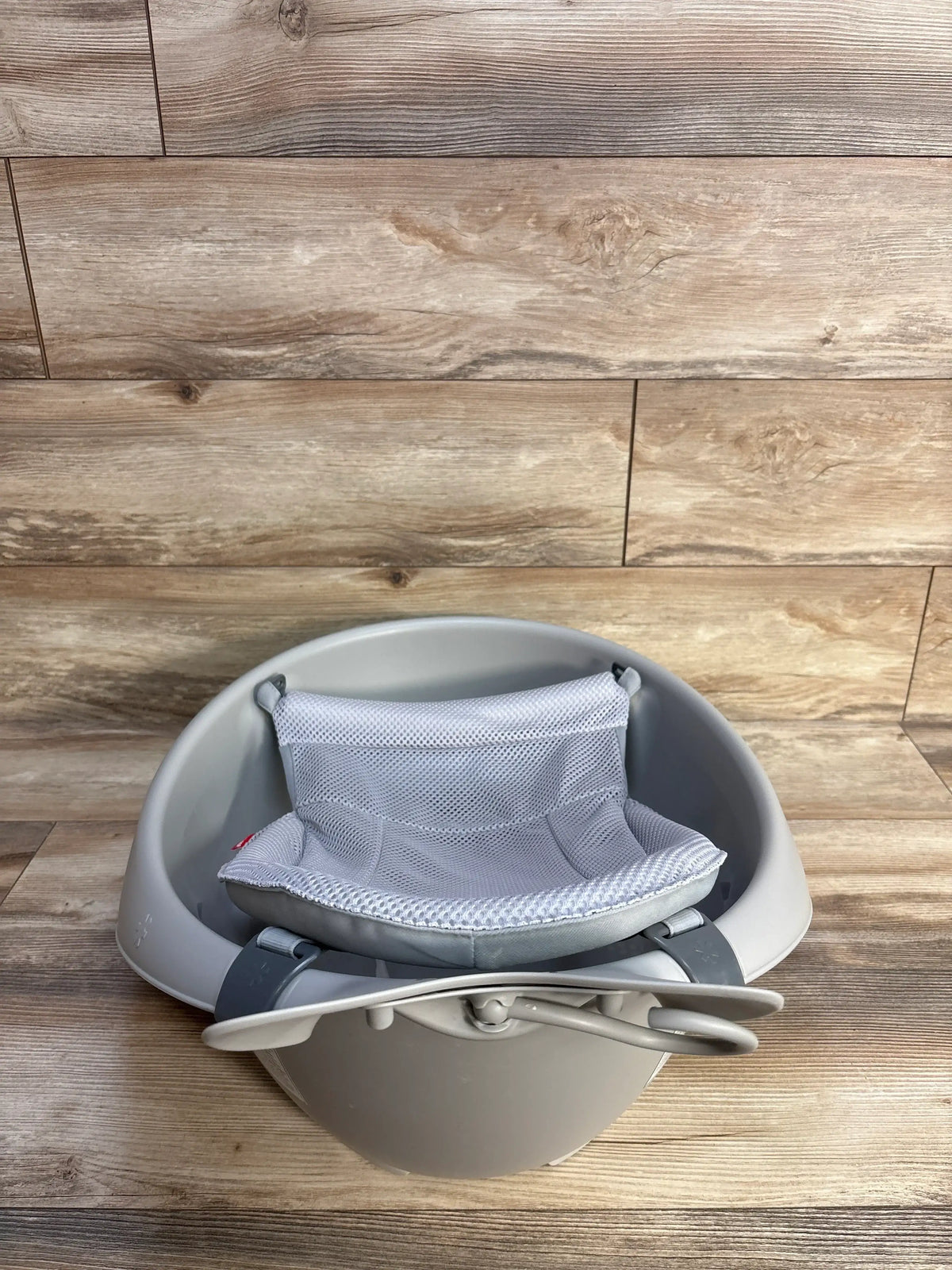 Front view of Skip Hop Moby Smart Sling three in one baby bathtub showcasing the gray mesh sling on a wood plank background