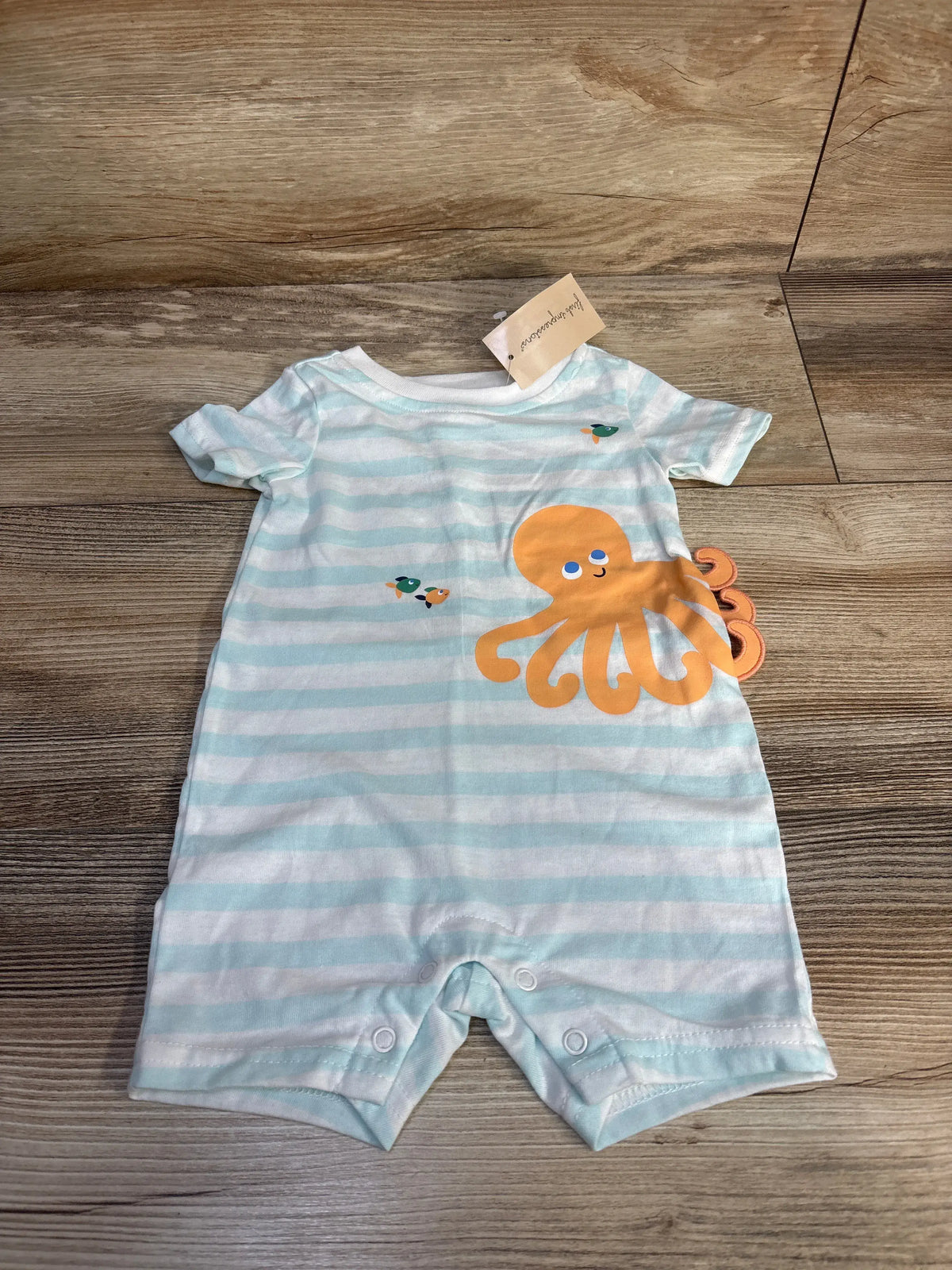 Front view of white First Impressions octopus romper showcasing light blue stripes and orange octopus graphic on a wood floor