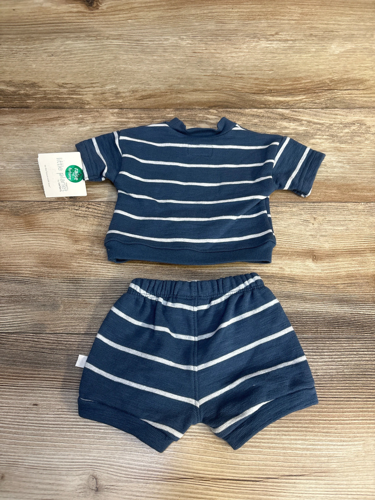 Navy and white striped baby outfit set with organic tag, laid on wood floor