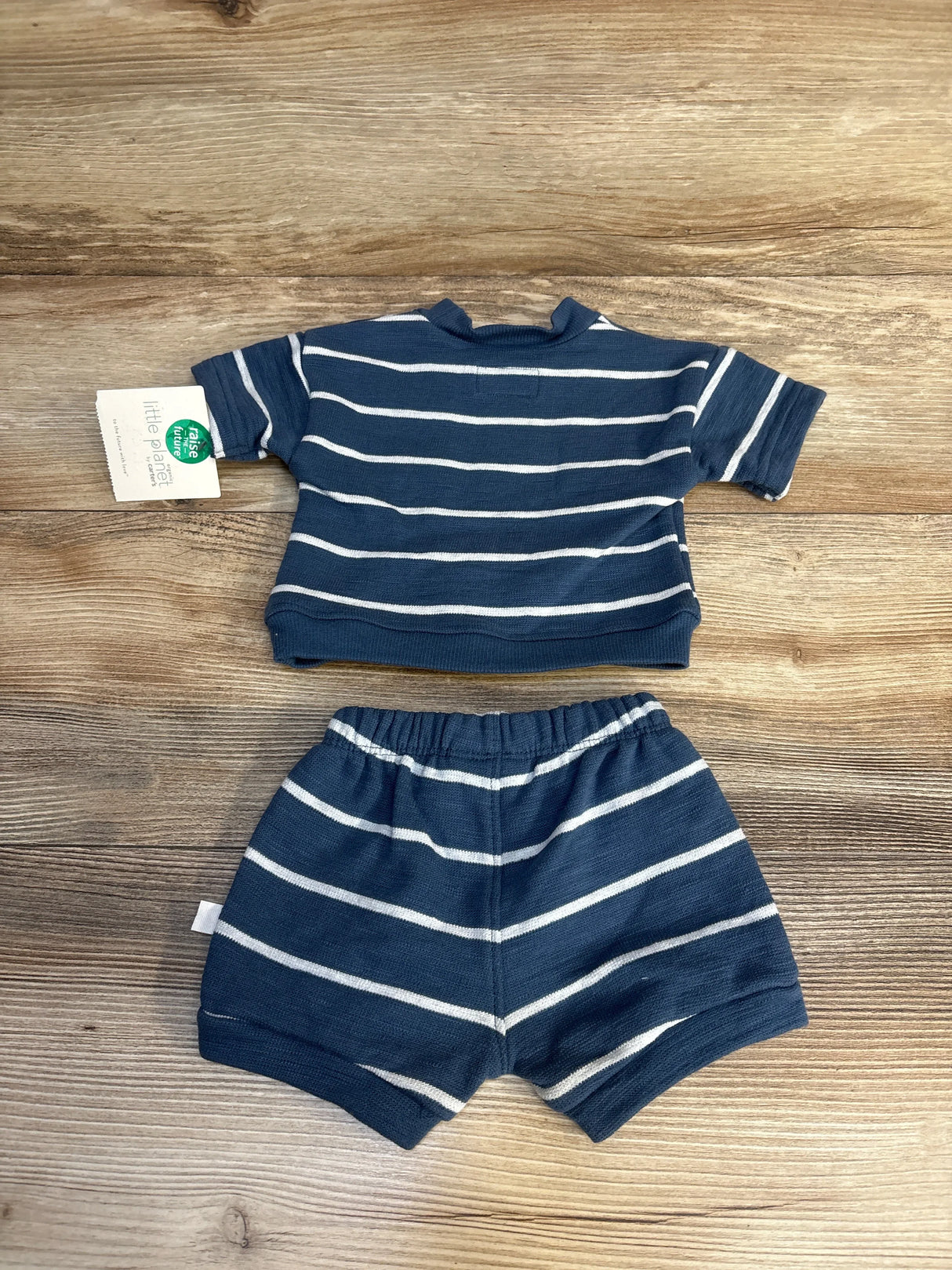 Top view of blue and white striped two-piece set with short-sleeve top, elastic waist shorts, and organic tag on wood floor
