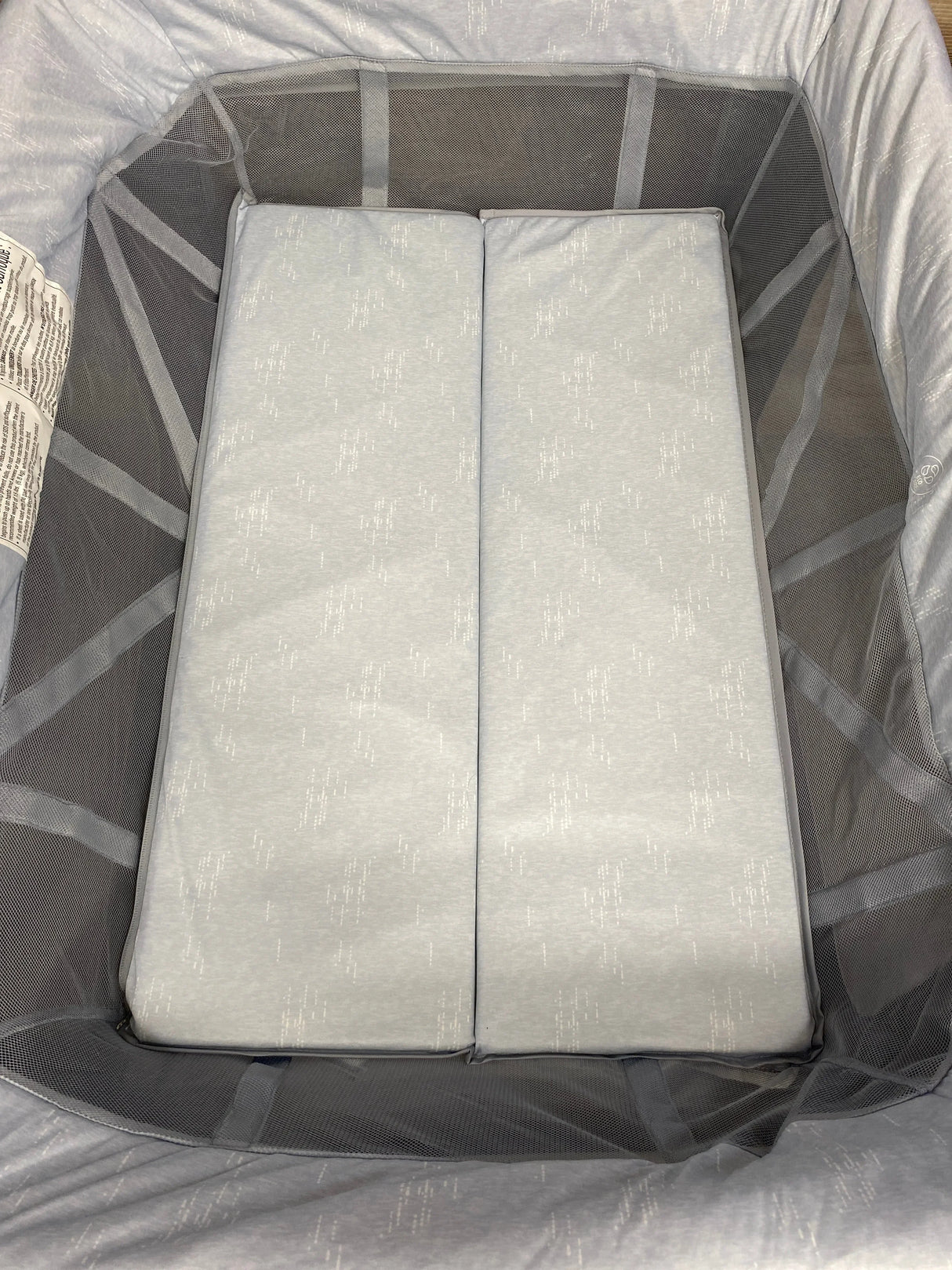 Top down view of Maxi-Cosi Swift Playard showing two-panel foldable mattress and mesh side panels on light gray interior
