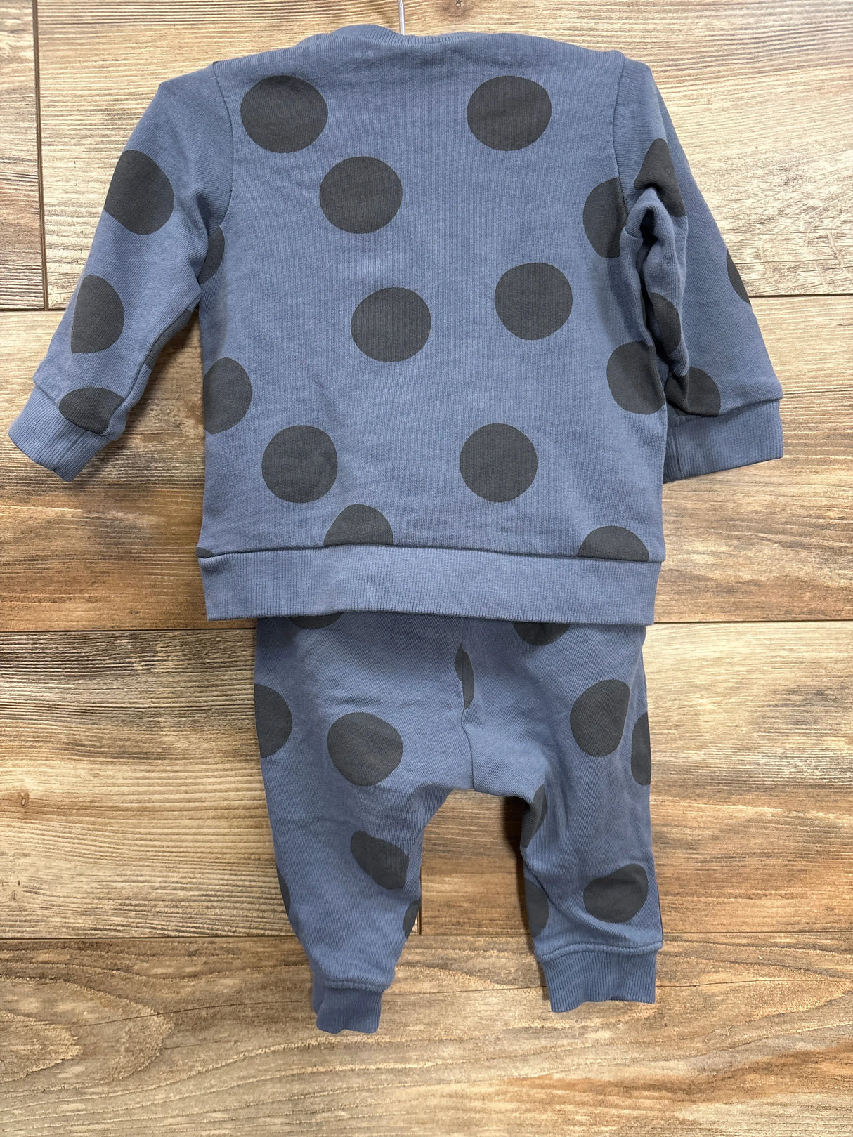 Blue toddler outfit with large black polka dots on sweatshirt and pants on wooden floor
