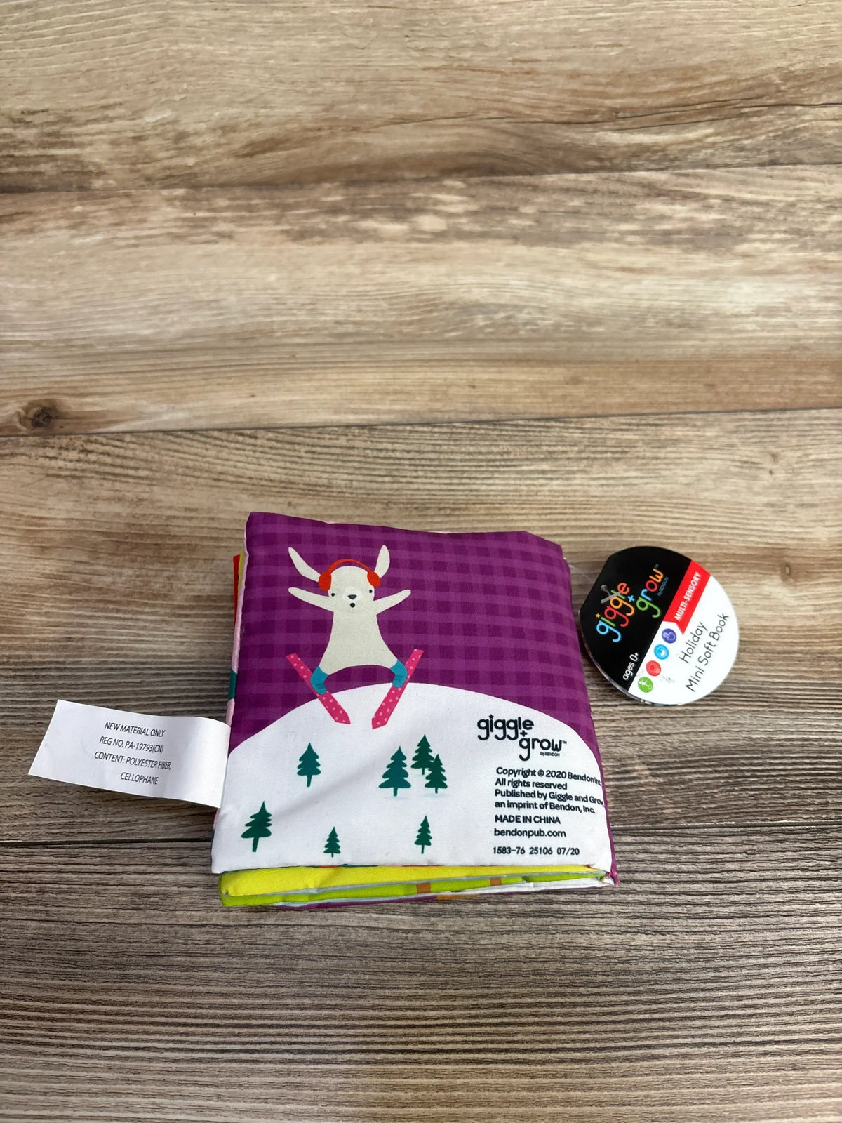 View of NEW Winter Fun Crinkle Book showcasing a skiing animal and snowy trees on a purple cover against wood