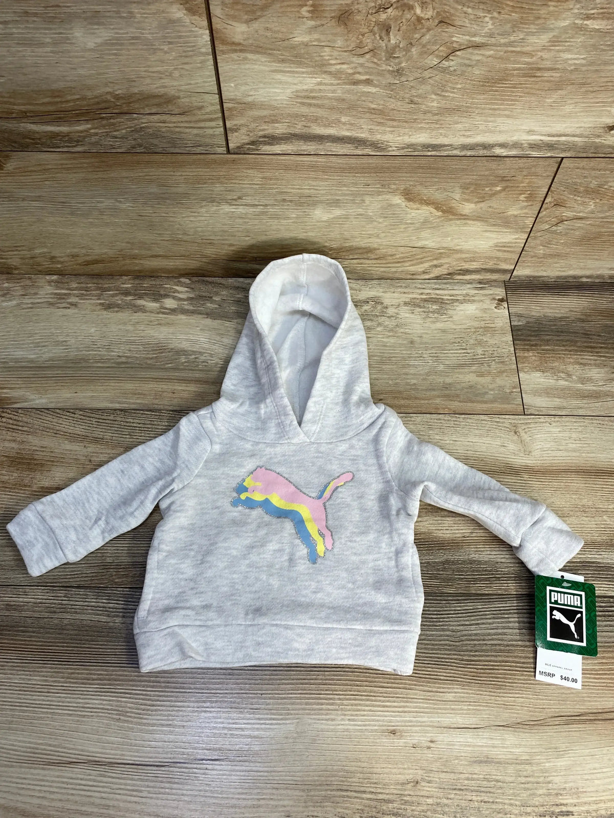 Gray Puma baby hoodie with pastel logo, price tag, on wooden floor