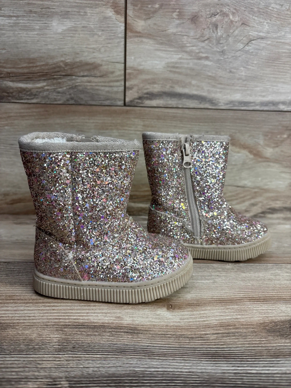 Side view of Cat & Jack toddler boots size 5C with gold glitter, side zipper and faux-shearling lining on wooden floor