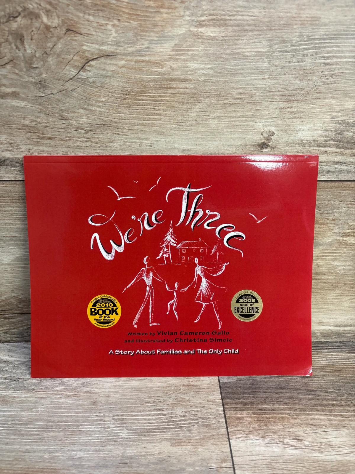Front cover of We’re Three: A Story About Families and The Only Child showing a family of three on a red cover