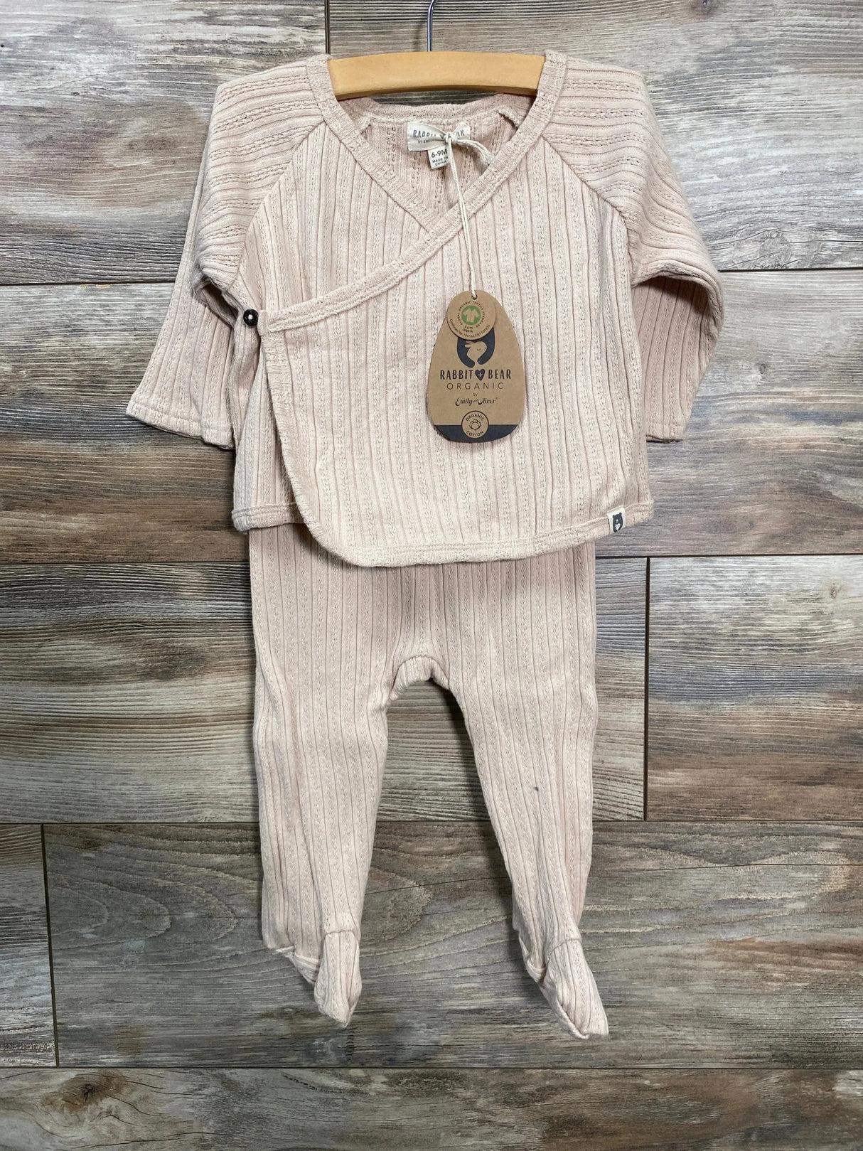 Front view of beige Rabbit and Bear kimono shirt and footed pants on hanger showing side snap and ribbed organic knit on wood