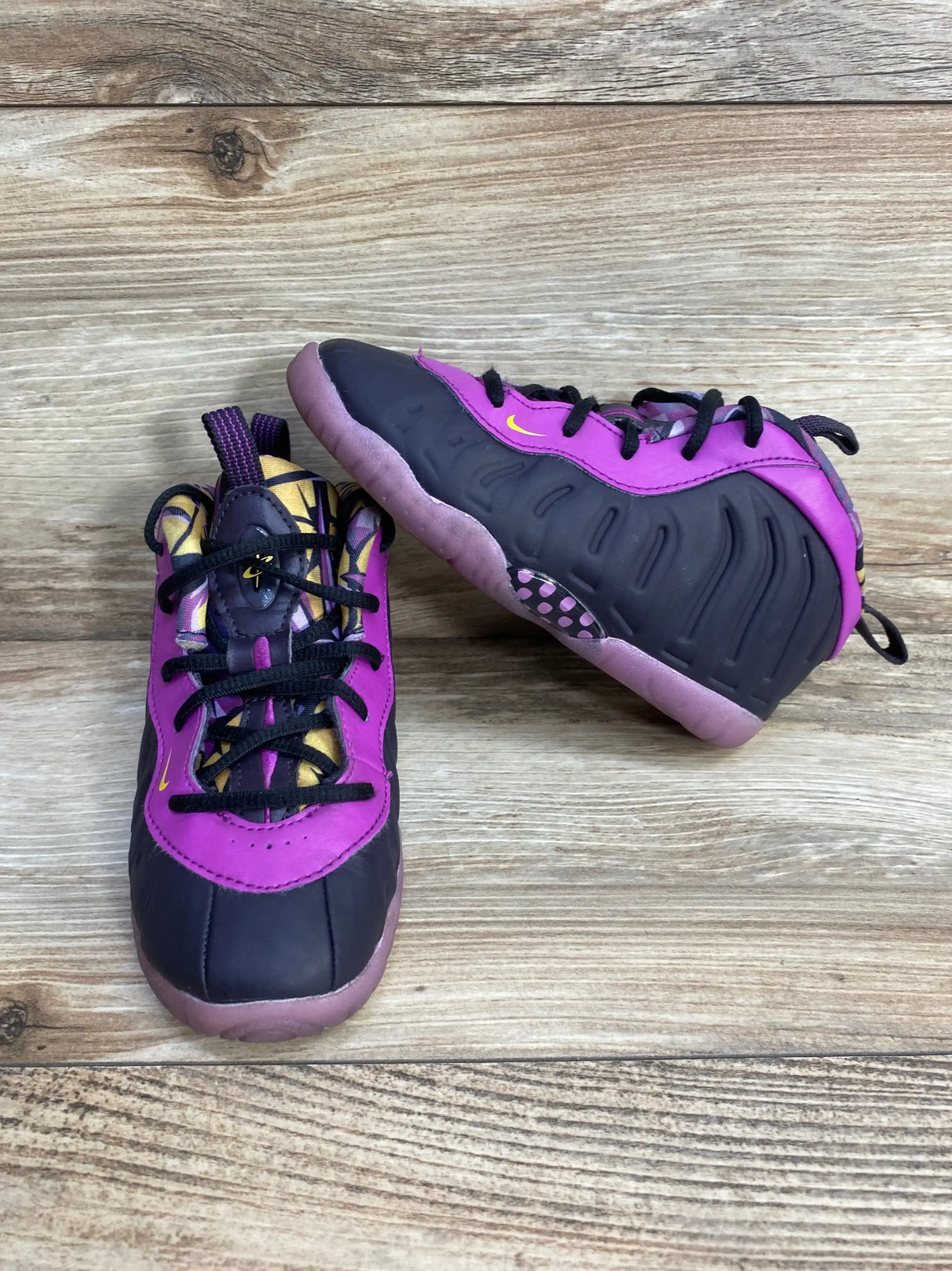 Front and side view of Nike Little Posite One toddler sneakers in Cave Purple showing ridged foam side and pink sole on wood