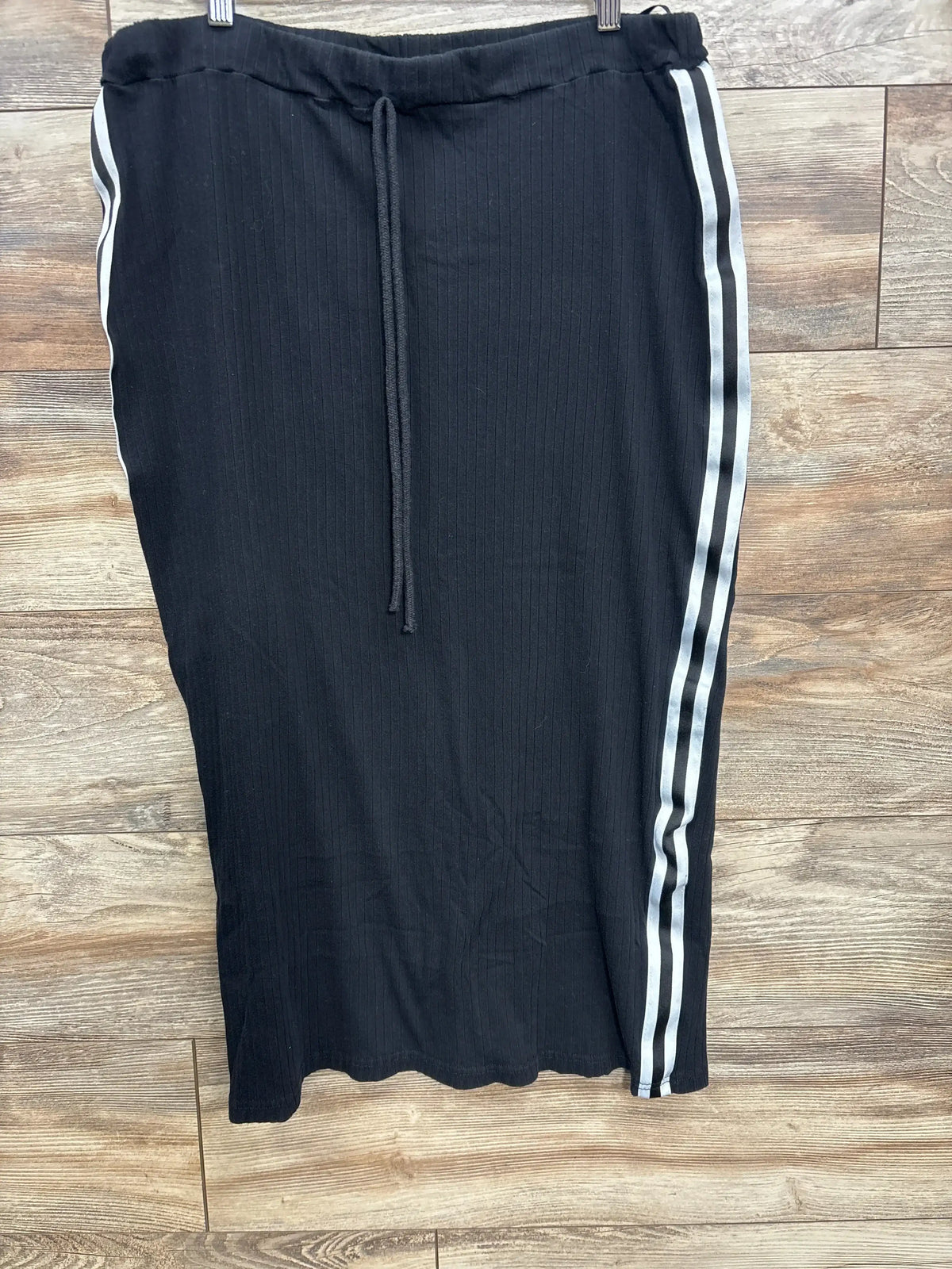 Black ribbed skirt with drawstring waist and white double side stripes on wooden floor