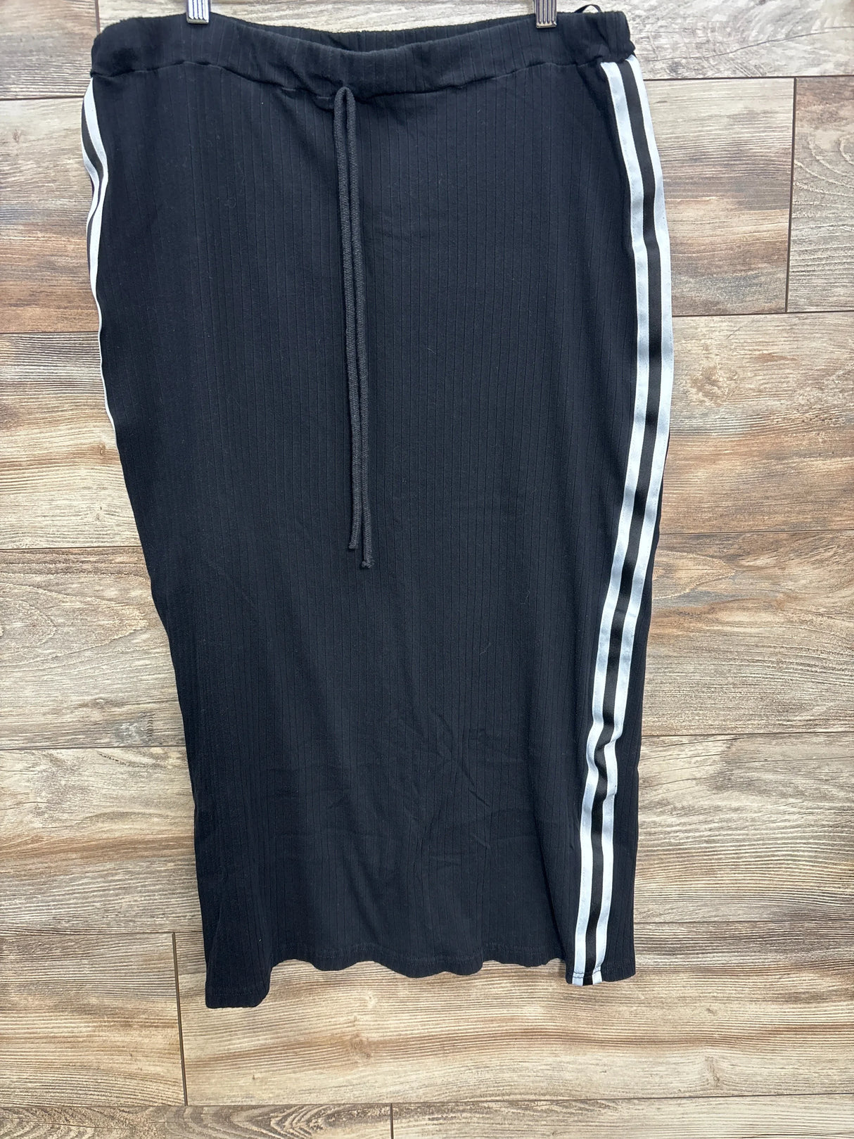 Black ribbed skirt with drawstring waist and white double side stripes on wooden floor