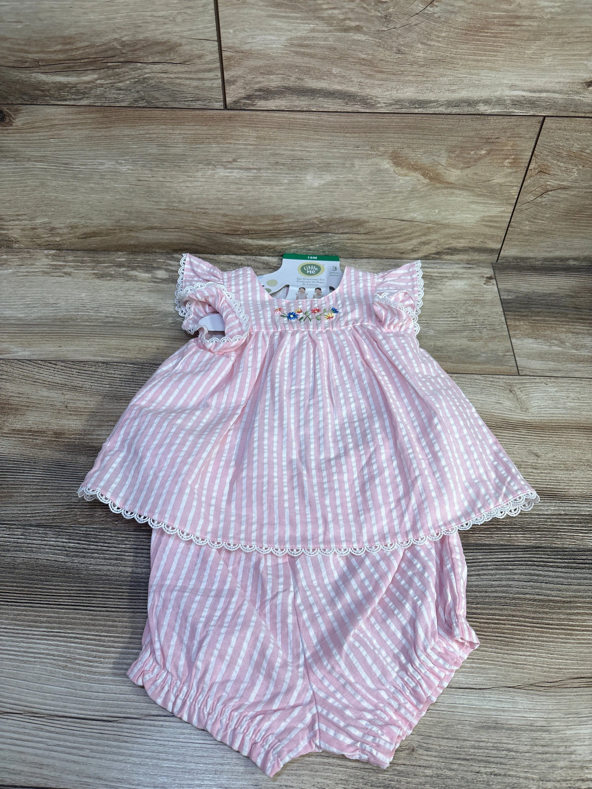 Top-down view of pink striped embroidered dress and bloomers, 18m, showing floral embroidery and lace trim on wood floor