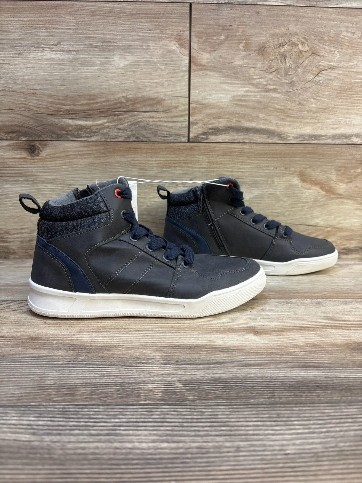 Kids navy blue high top sneakers with white soles and side zipper on wooden floor