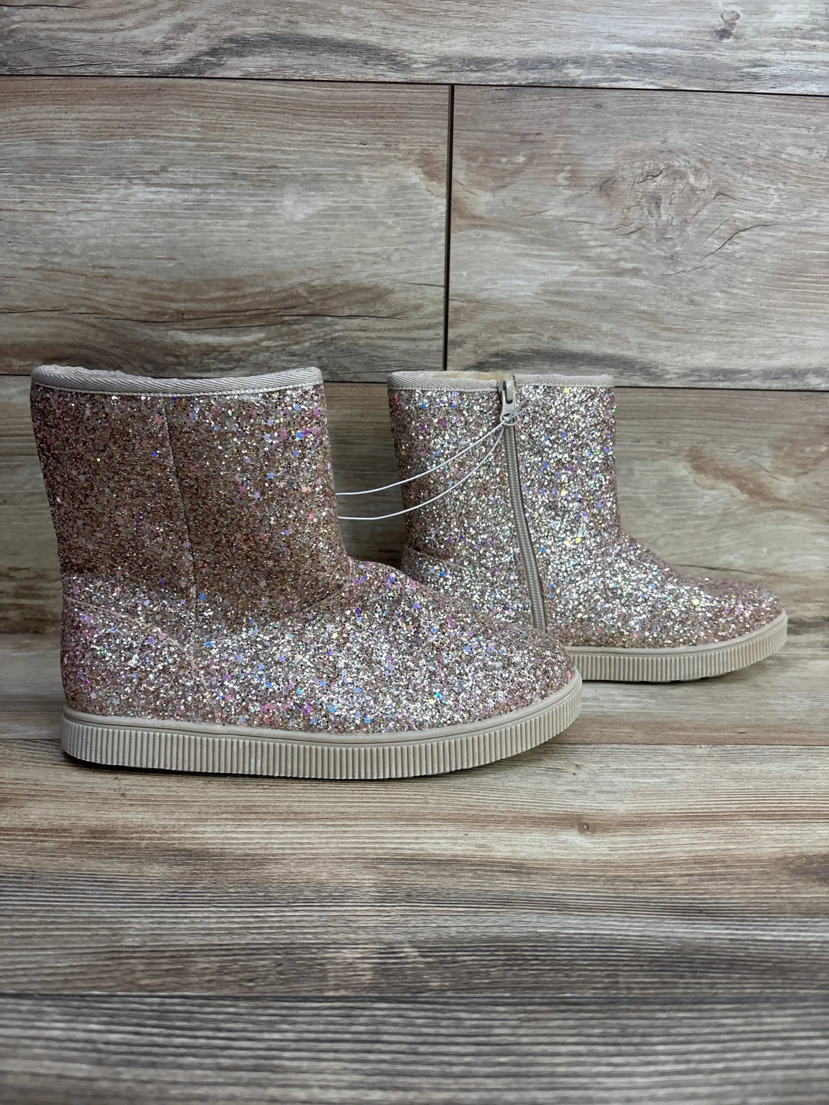 Side view of Cat & Jack Holland shearling boots, size 5Y, glittery rose-gold showing side zipper and sole on wood background